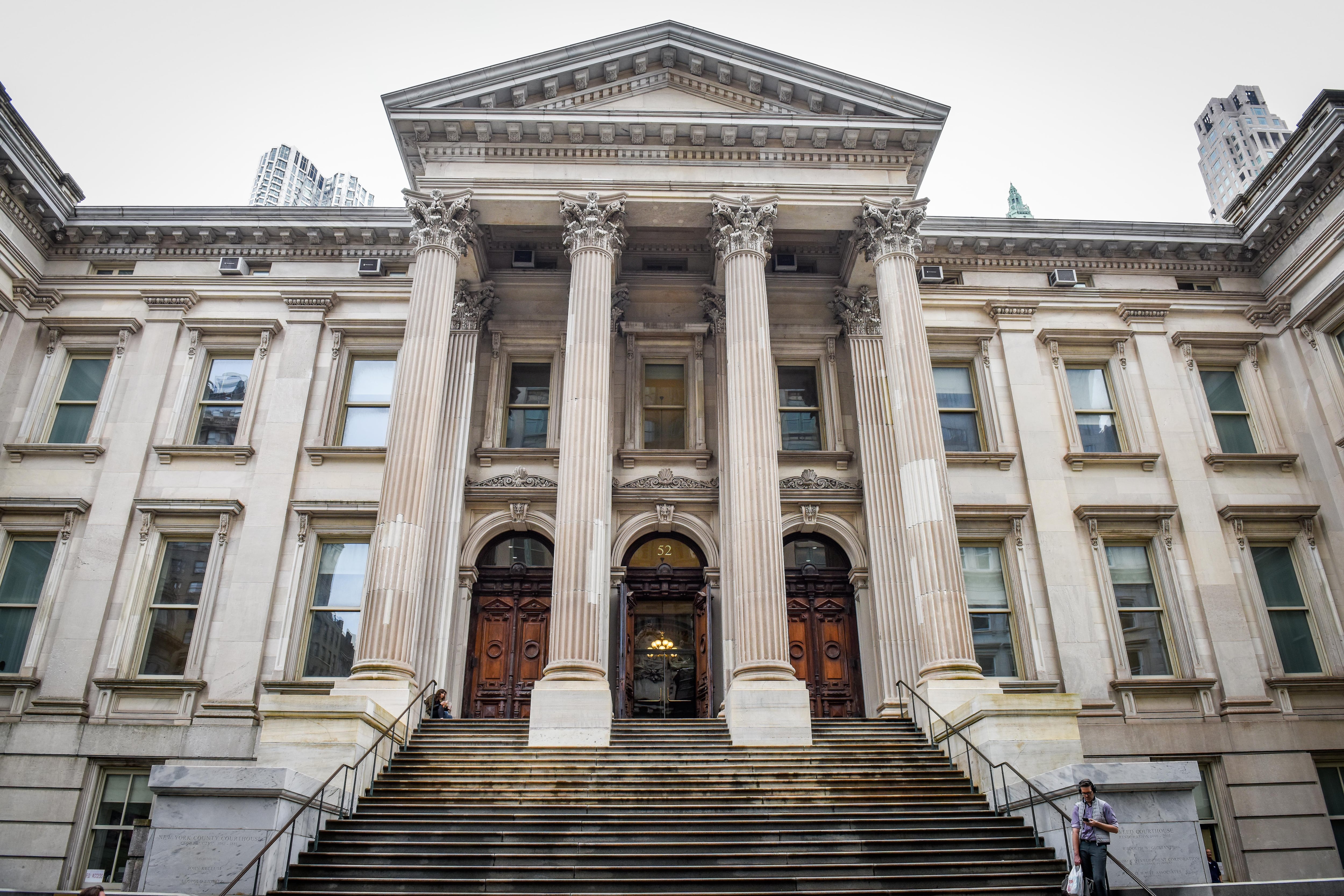 The front entrance to a large, tan stone building with columns.