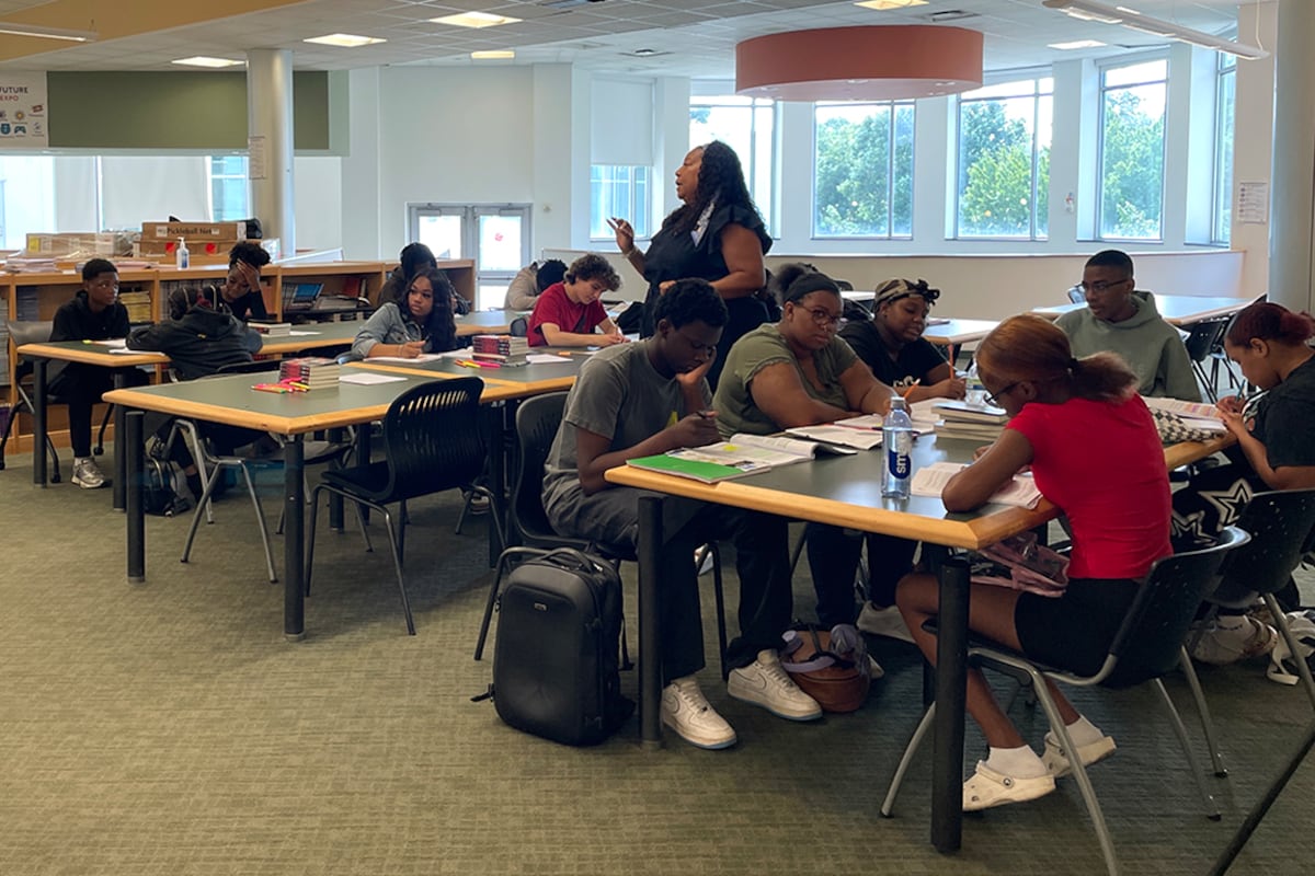 A woman talks to students at tables.