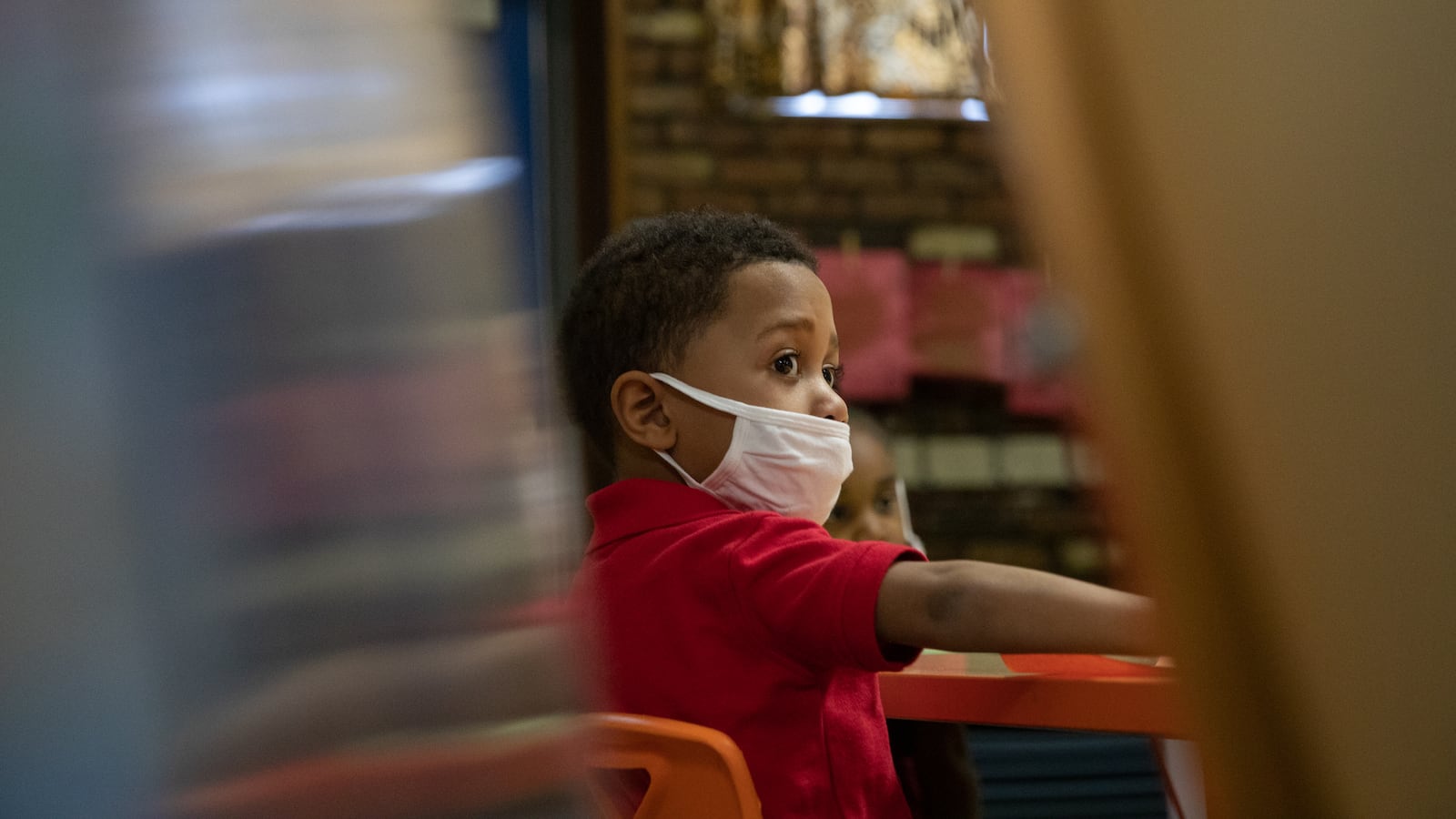 A preschooler listens to instructions for a painting activity during a preschool class at Little Scholars child care center.