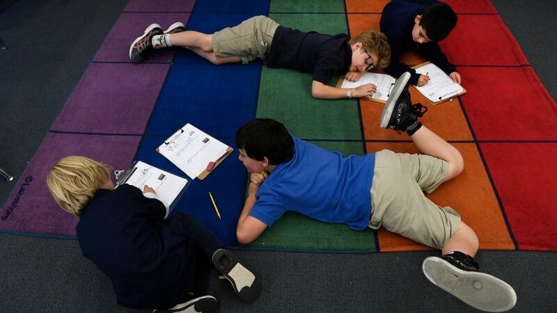 Third-grade students at the Denver Language School do schoolwork on the floor.