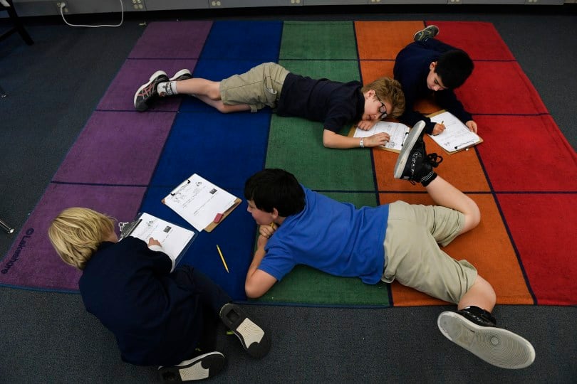 Third-grade students at the Denver Language School do schoolwork on the floor.