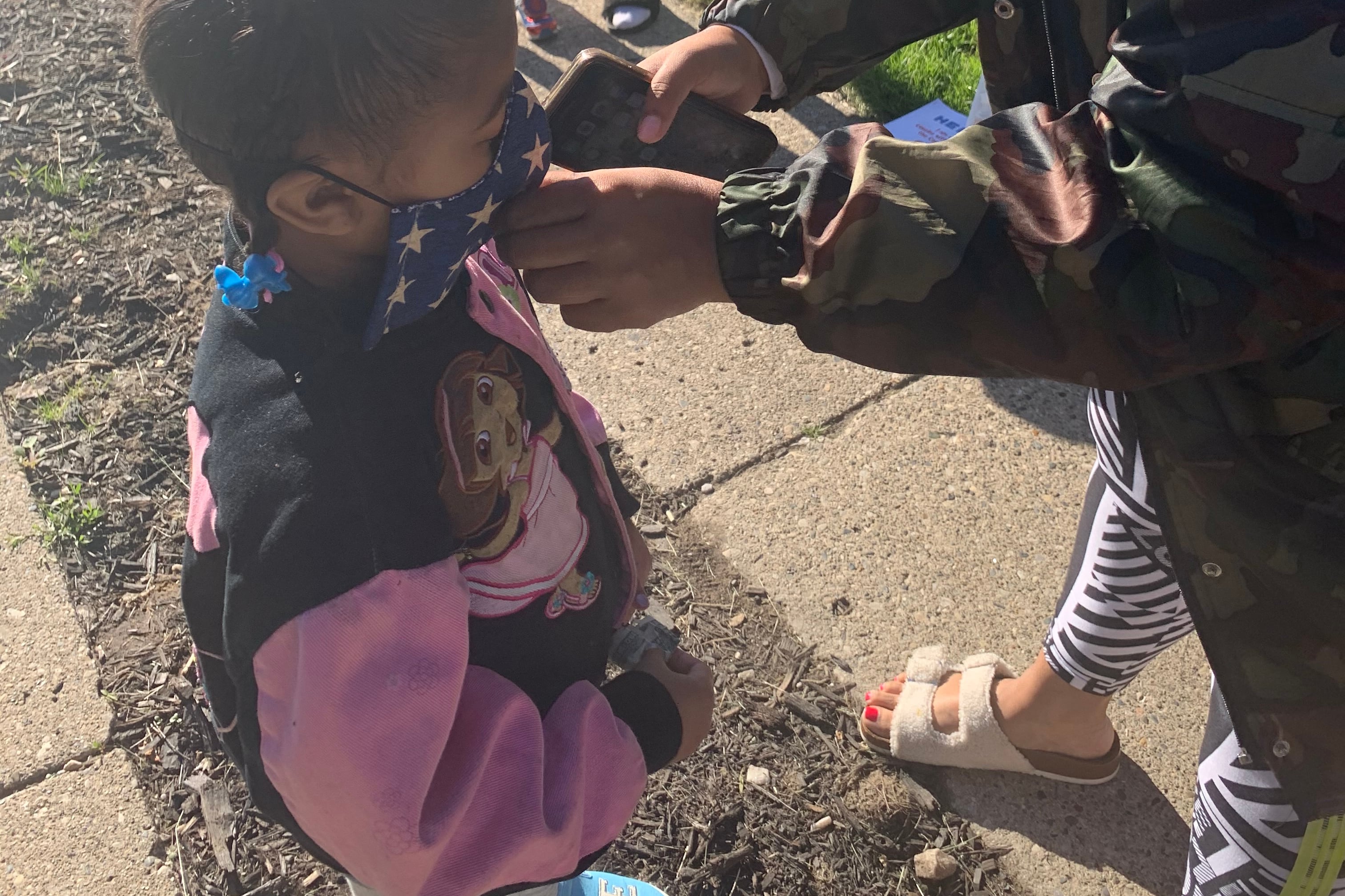Mother places mask on child’s face before preschool during the coronavirus pandemic