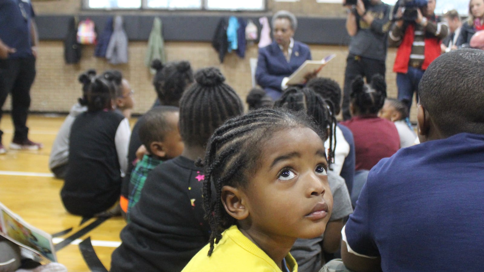 A student spending Wednesday morning at Kennicott Park in Kenwood glances up at media cameras as Mayor Lori Lightfoot reads a book aloud to a group of children during the 10th day of the teachers strike.