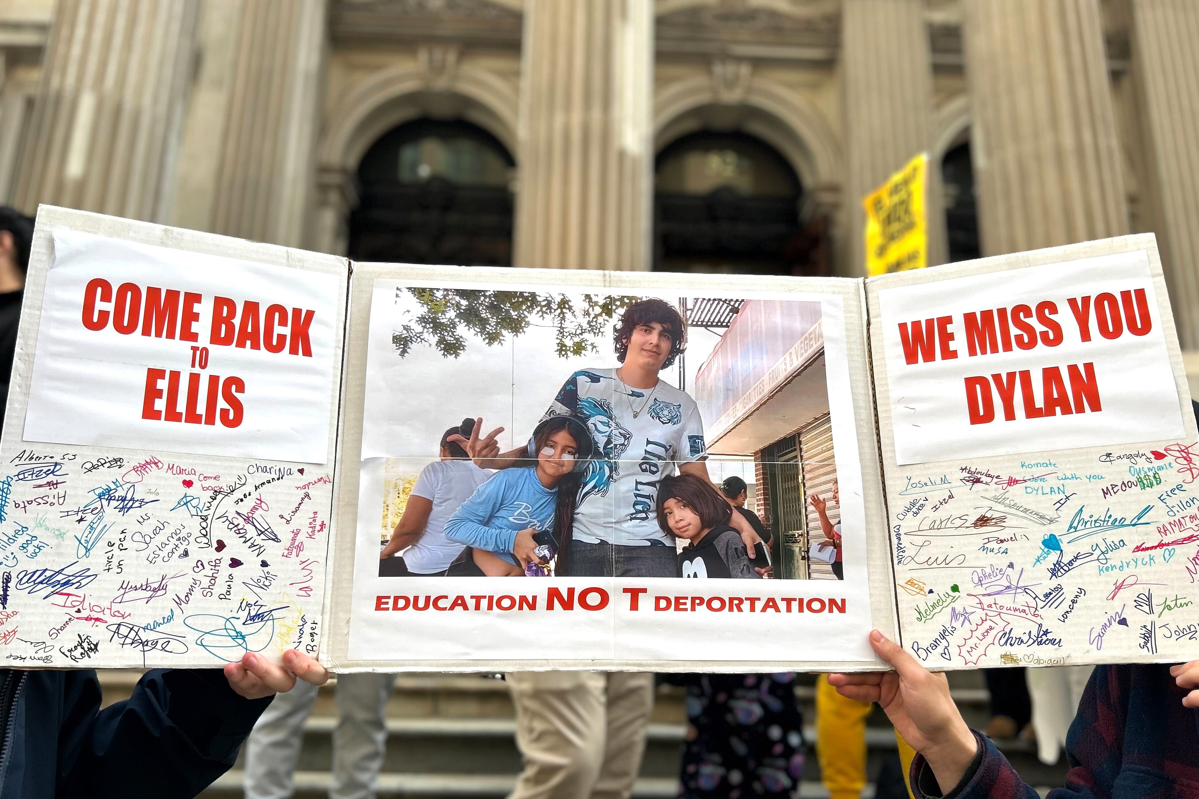A giant card with signatures is displayed on the steps of a building.