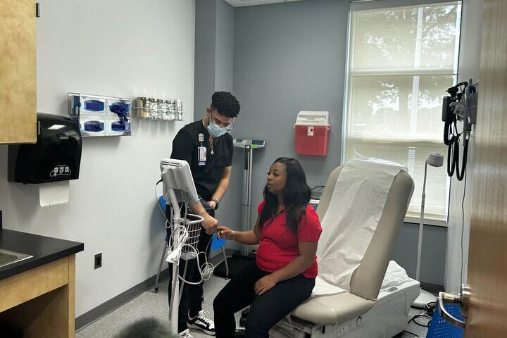 A male nurse examines a woman at a school-based health center.