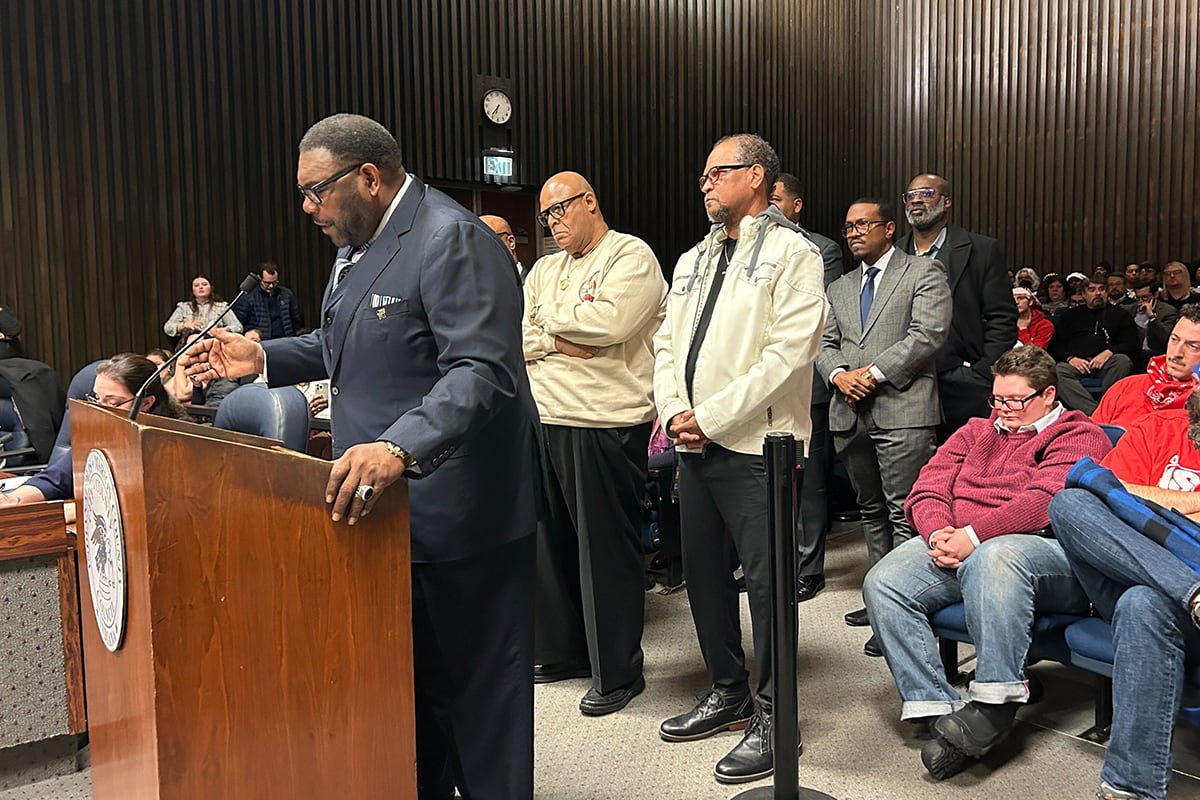 A man speaks from a podium surrounded by others.