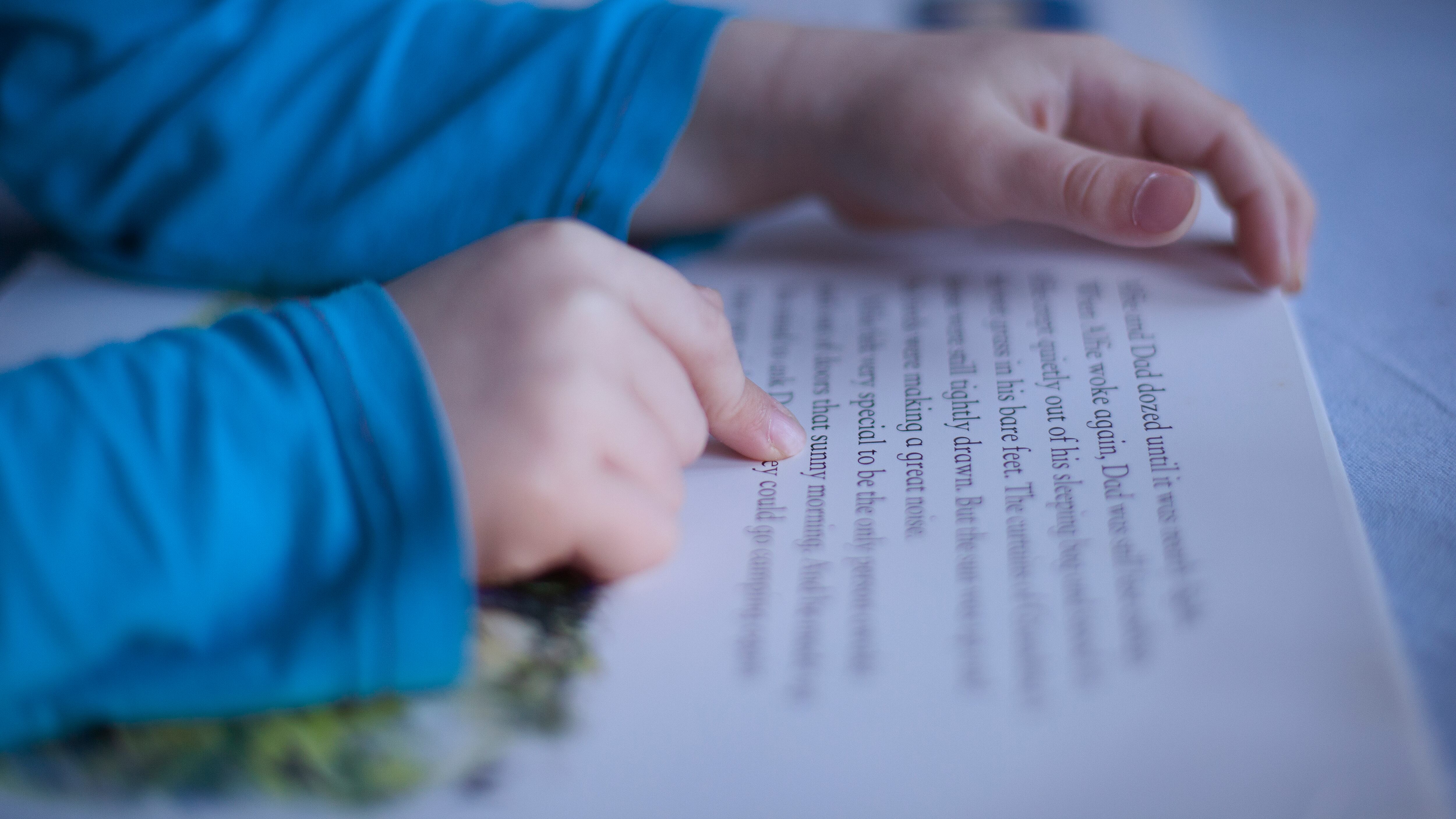 Close up of boys’ fingers pointing to words in book