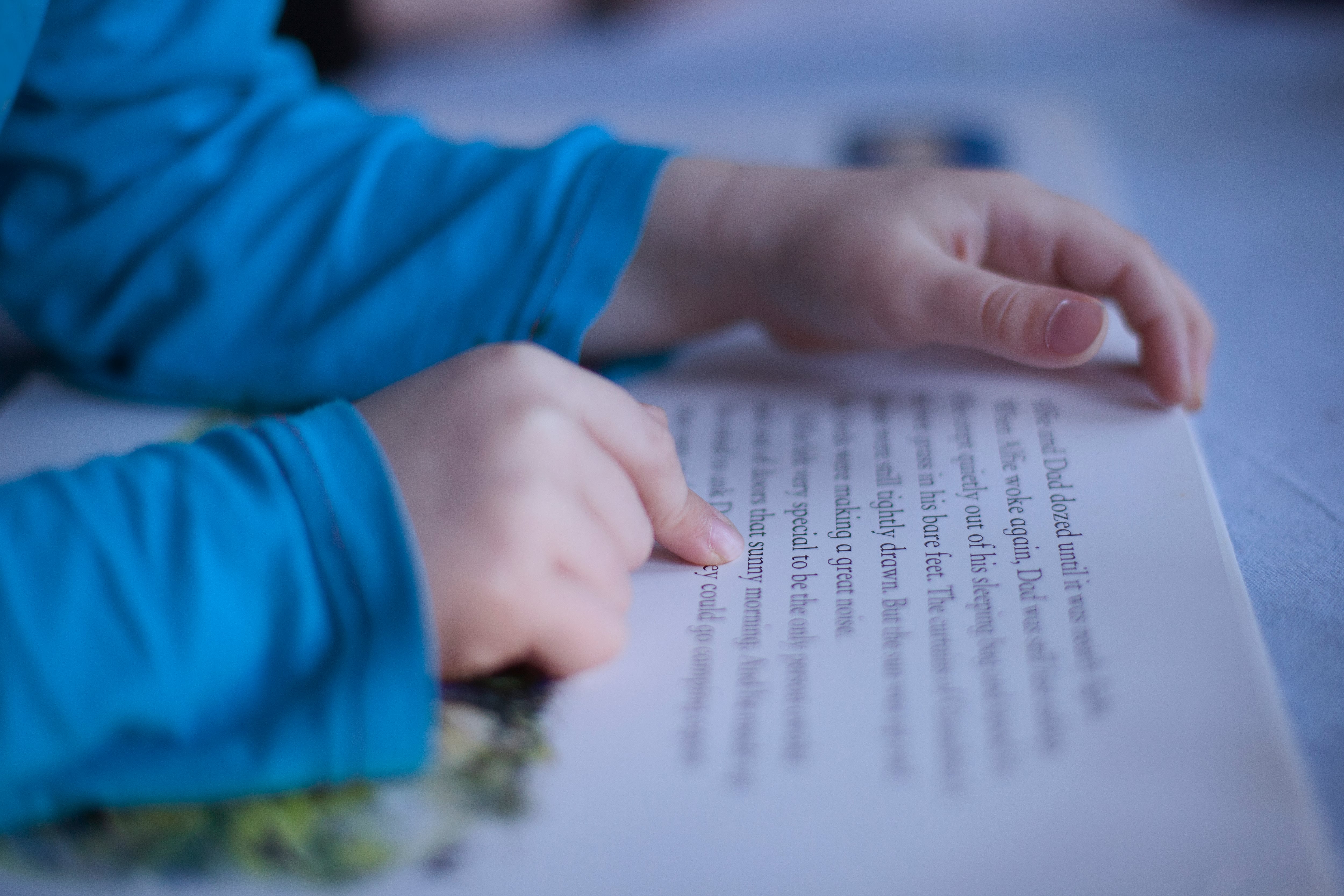 Close up of boys’ fingers pointing to words in book