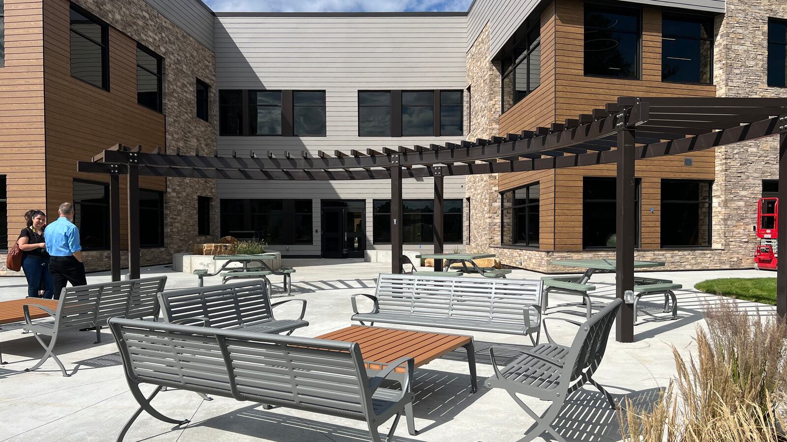 An outdoor area with metal seats with a large building in the background.