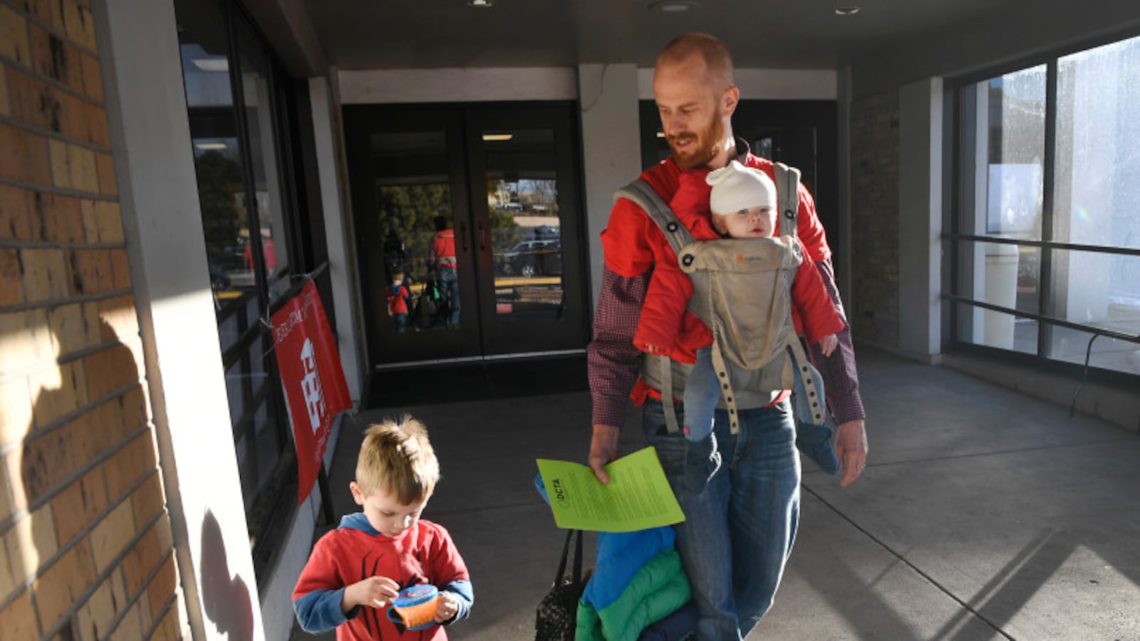 Skinner Middle School math teacher Peter English walks out of the Riverside Baptist Church with his son, Landon, left, and daughter Brooke strapped to his chest after voting on whether to go on strike ()