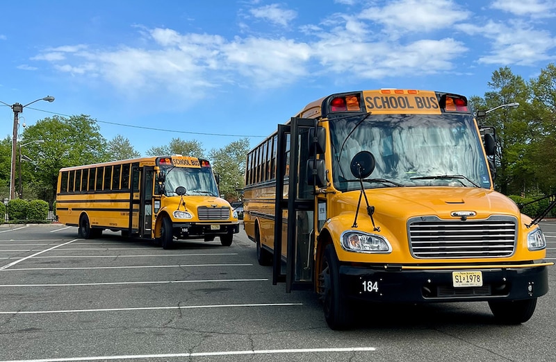 Two yellow buses are parked in a parking lot.