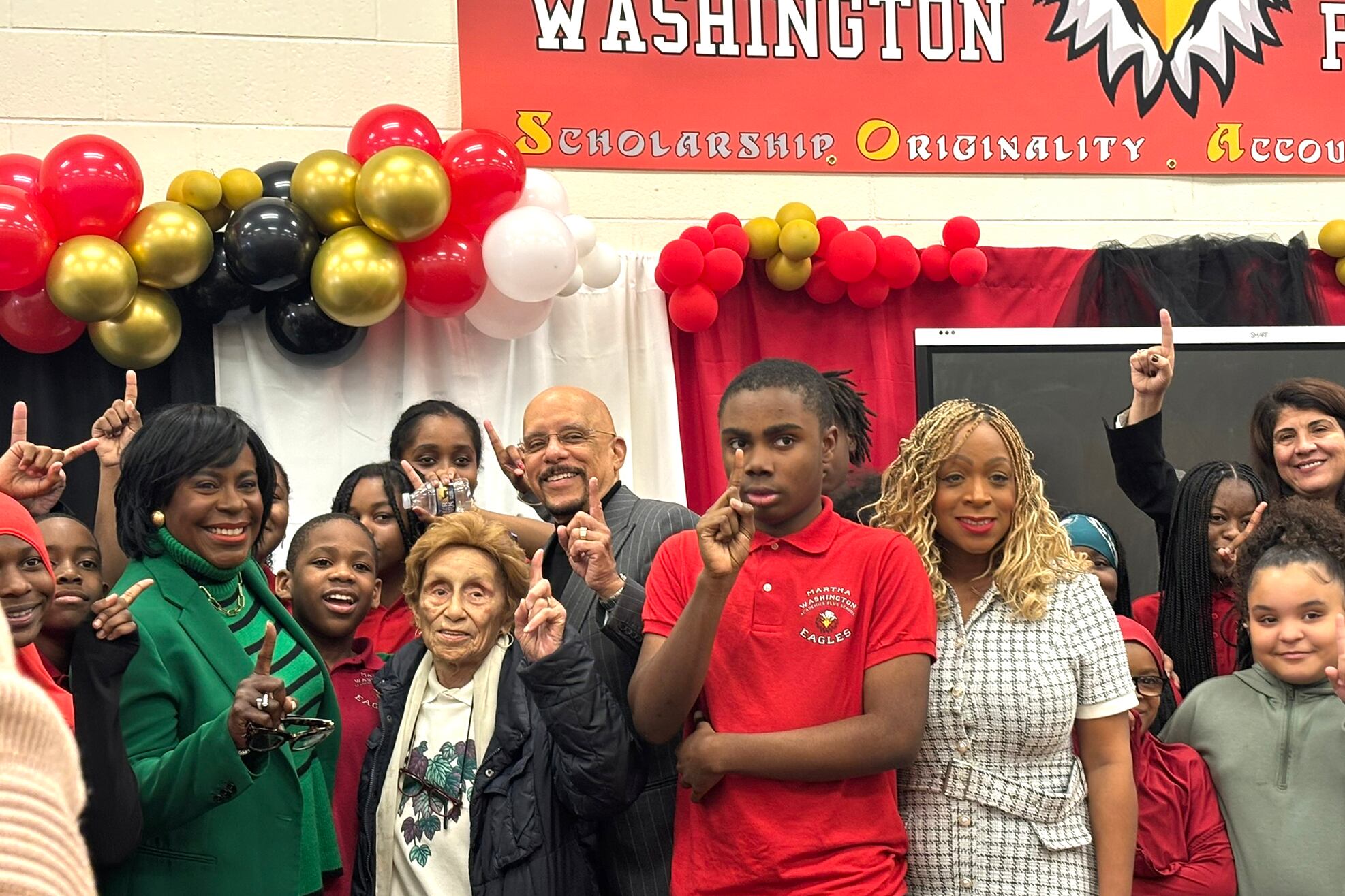 A group of people stand in front of a red sign.