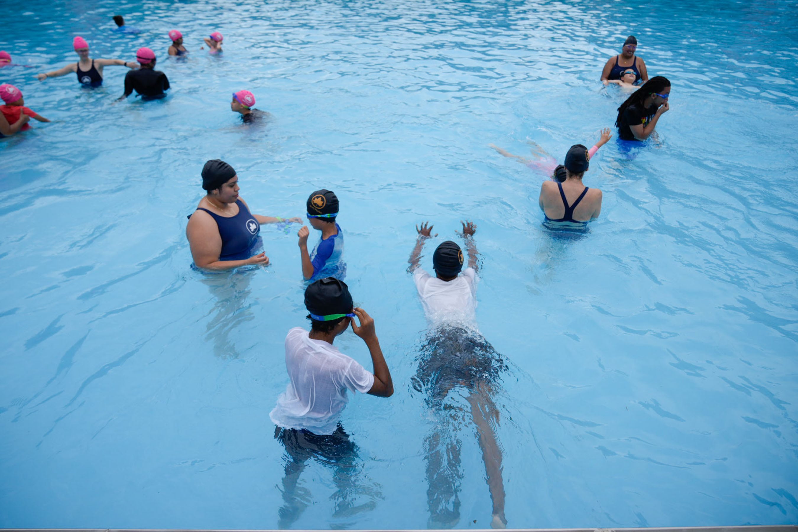 A group of people inside the pool are swimming.