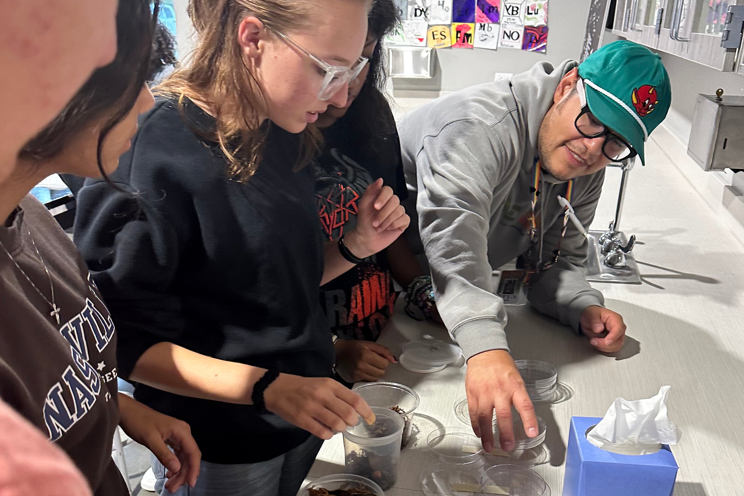 High school students look down at a science experiment on a counter.