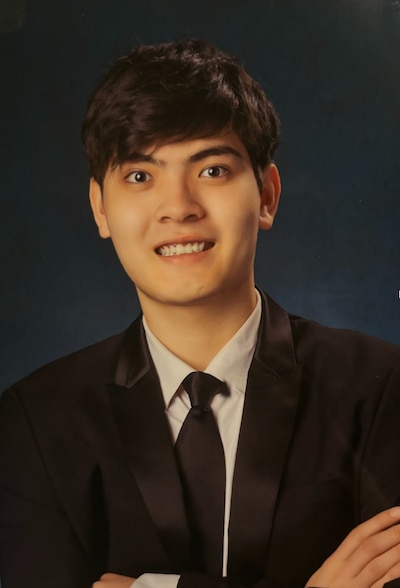 In this headshot, a young Asian male wears a black suit, a white shirt, and a black tie.