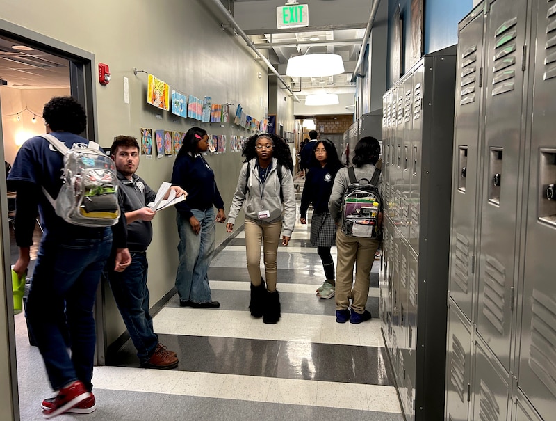 A photograph of high school students walking down a school hallway.
