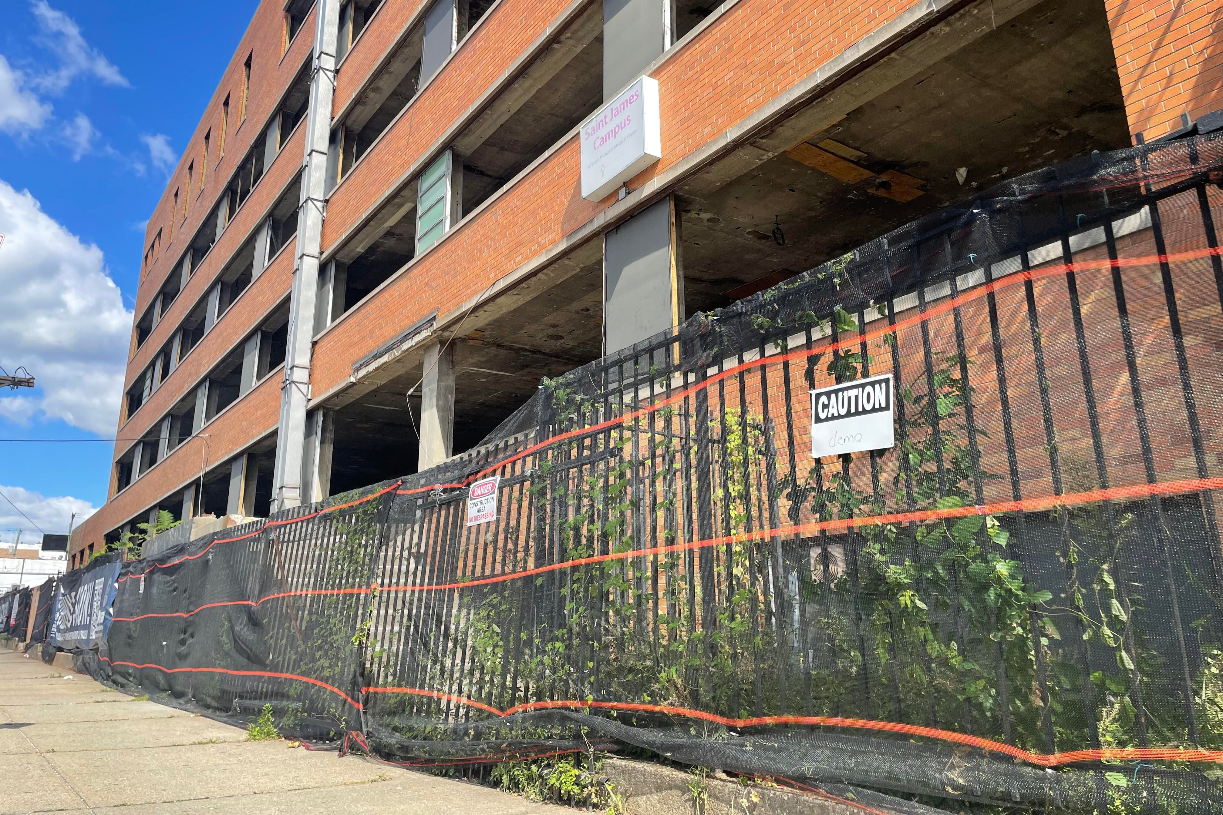A four-floor building with red brick and exposed floors is housed in a fenced-off property.
