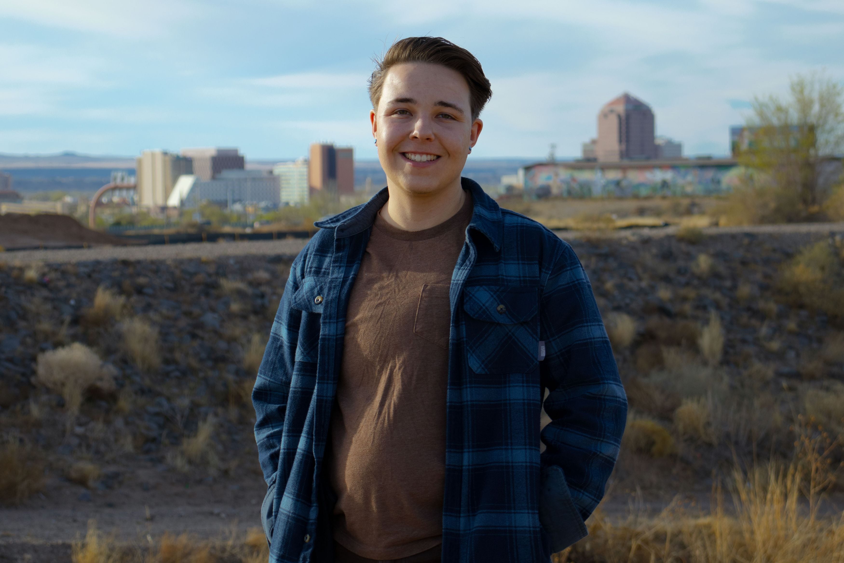 A college student stands in front of the Albuquerque, New Mexico skyline.