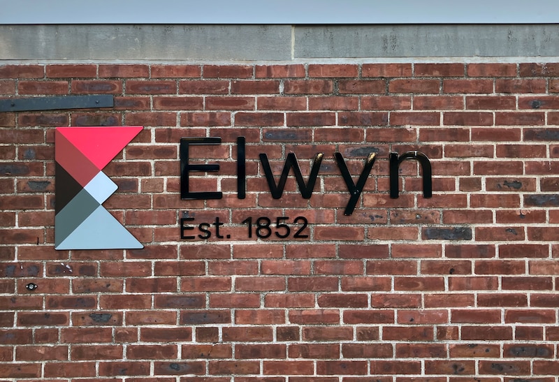 A photograph of a brick wall with a logo on it.