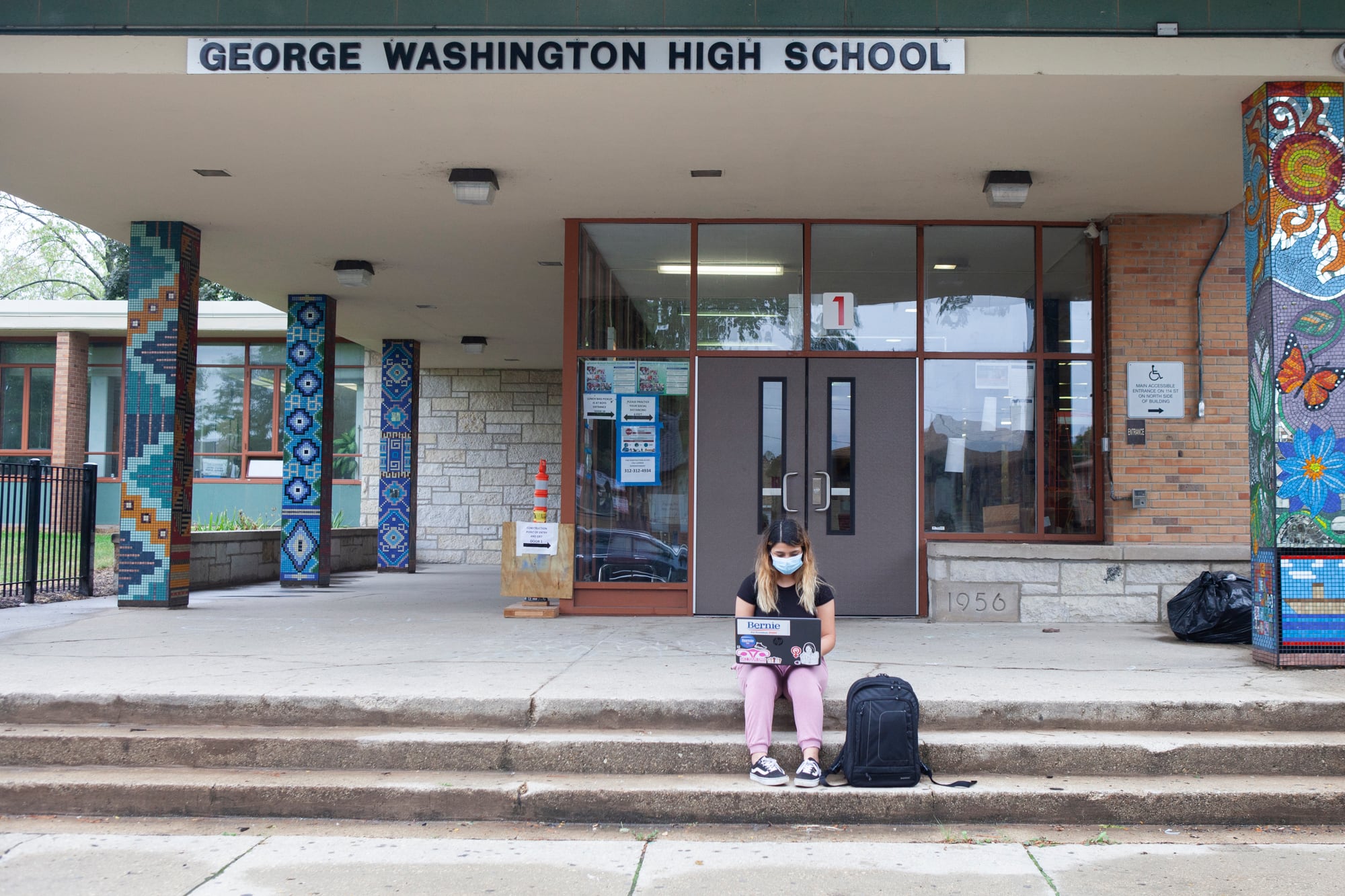 Trinity sitting on steps outside of school with her backpack and laptop.