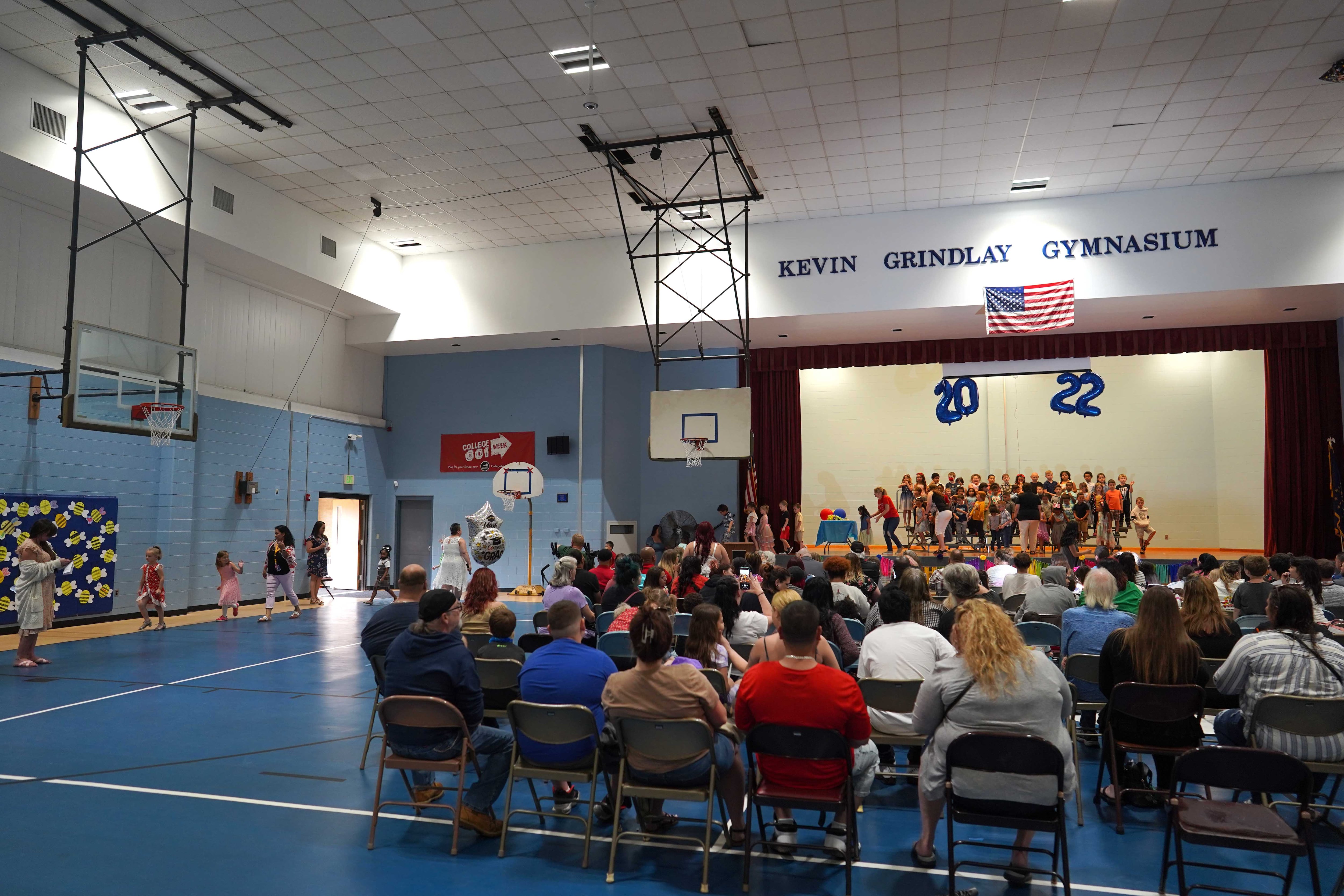 a gym of people in chairs waiting for a graduation ceremony