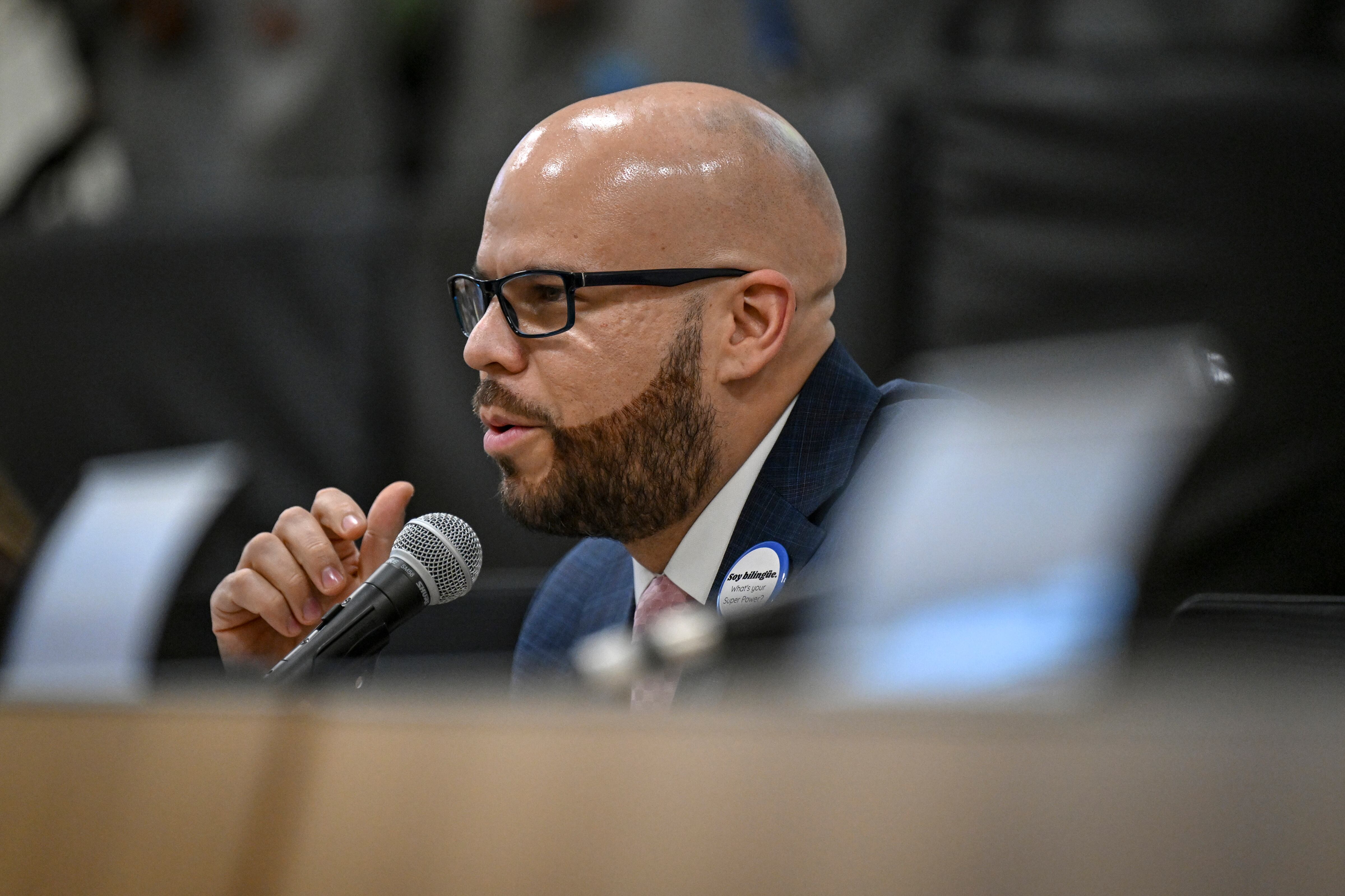 A man in a suit speaks from behind a microphone.