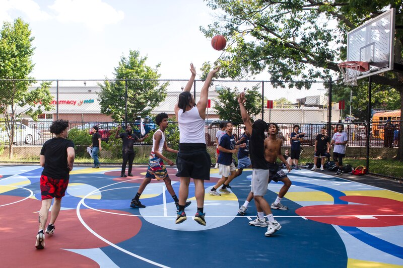 Young men play basketball on a brightly-painted court.