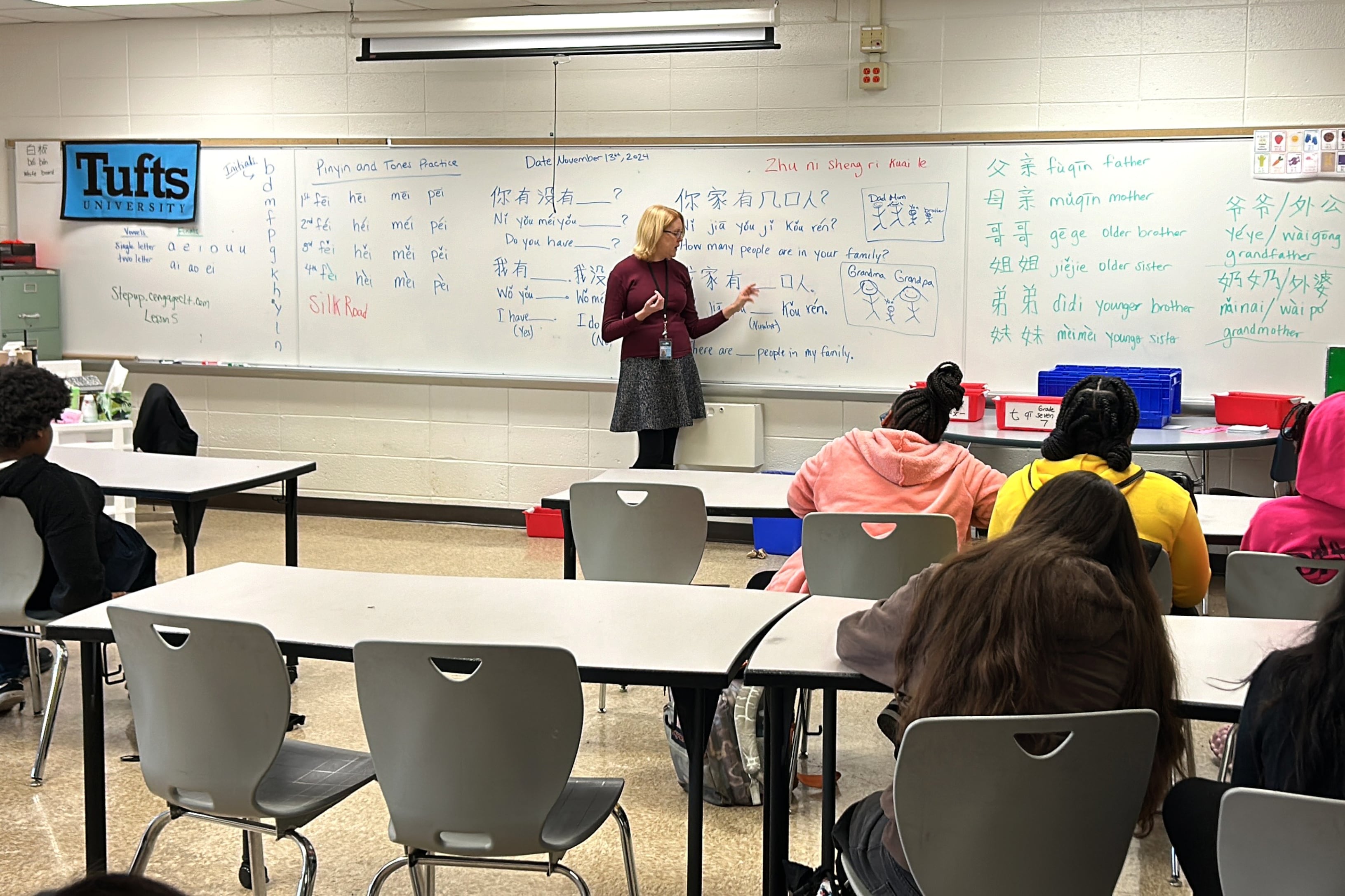 A woman stands in front of a whiteboard in a classroom.