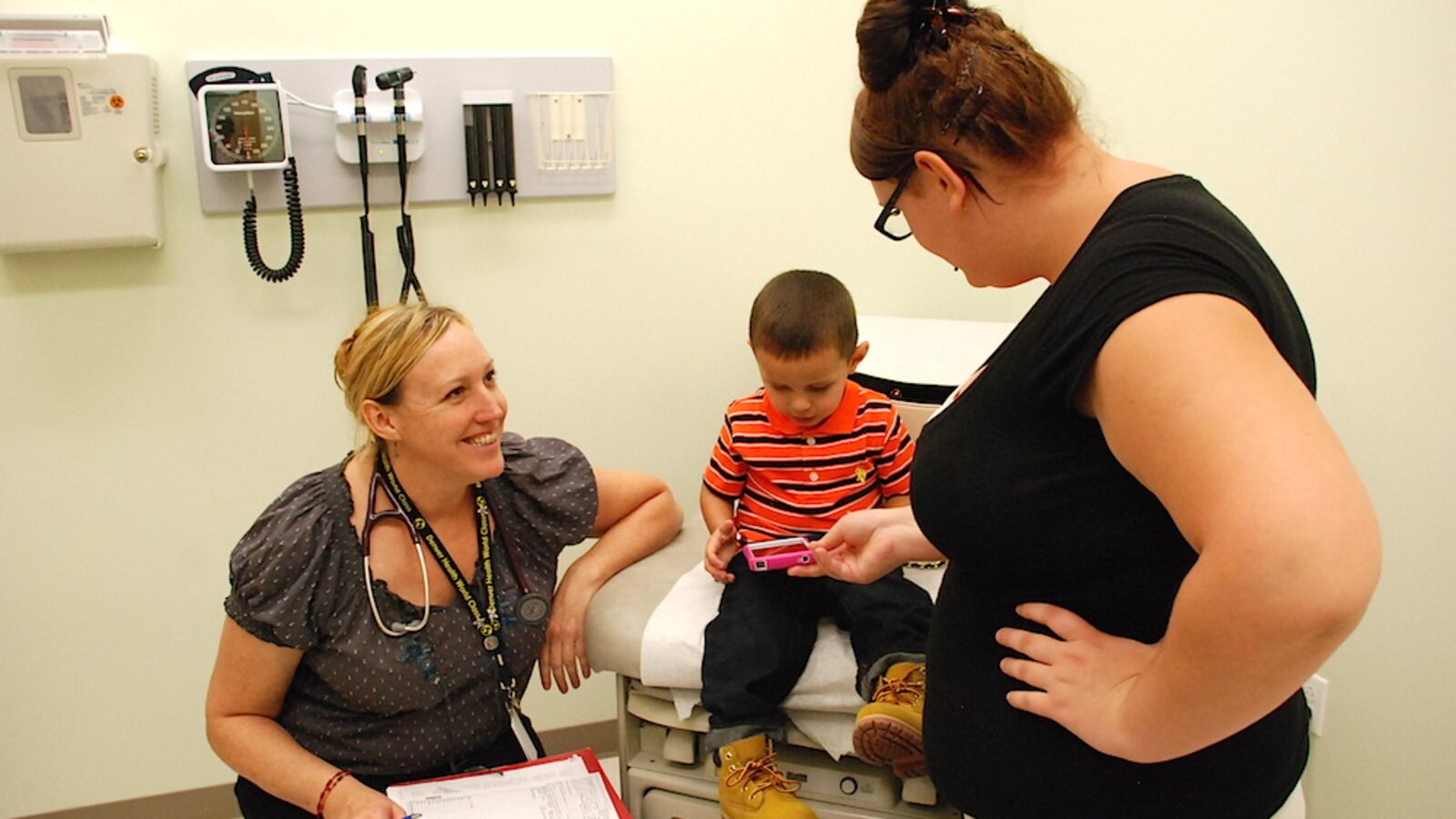 Physician's Assistant Elizabeth Madrid chats with Jade-Marie Burgess and her son Eli at the school-based clinic at Florence Crittenton High School.