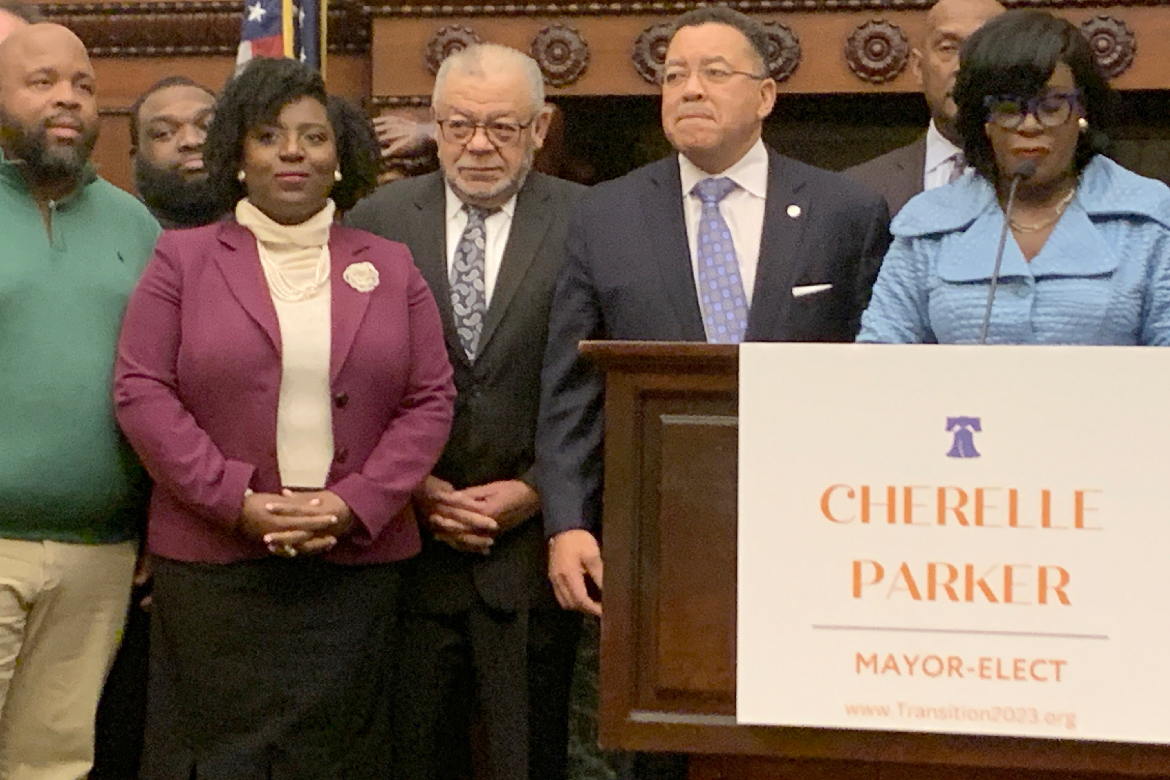 Seven people are standing side-by-side in a conference room with a podium in the foreground.