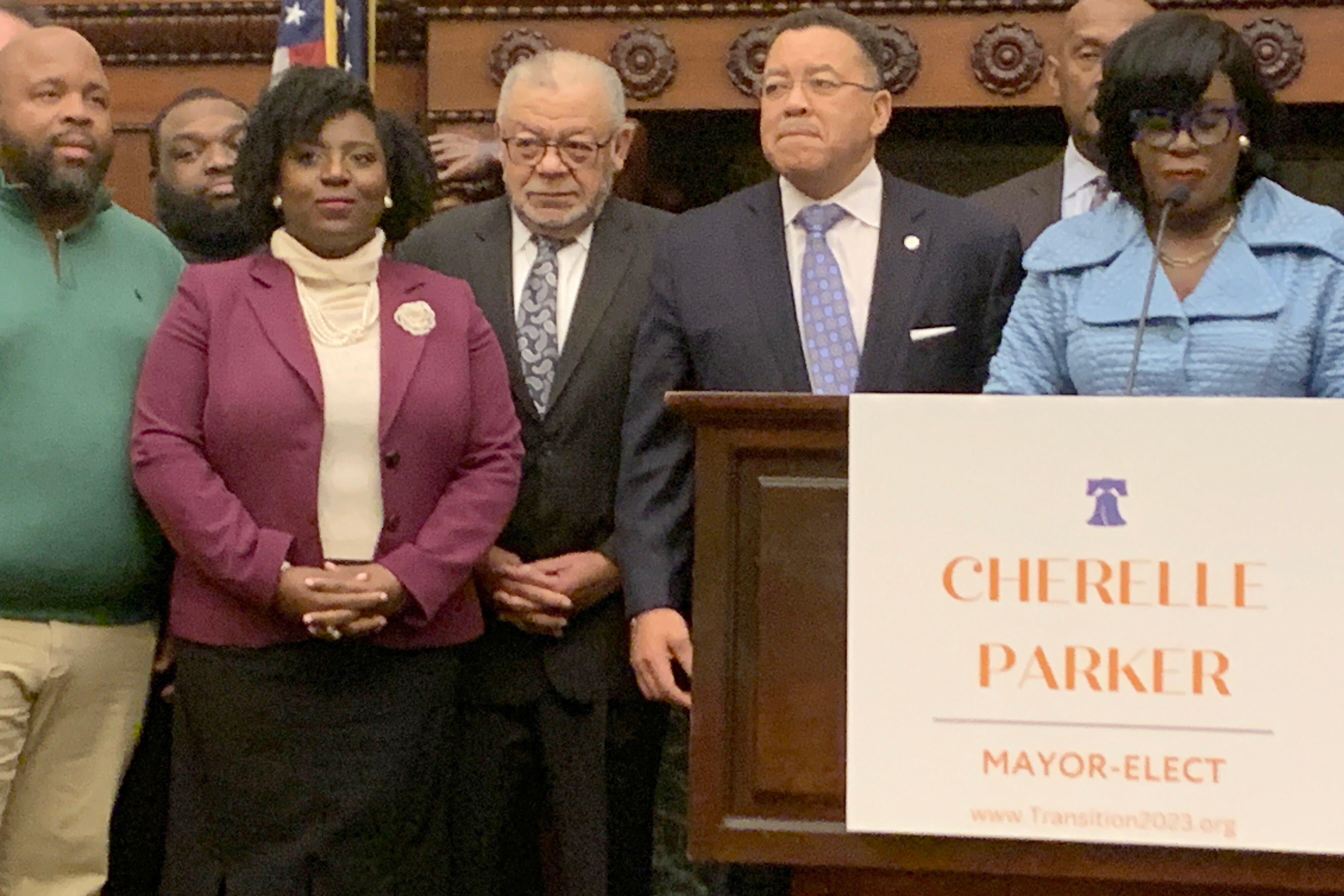 Seven people are standing side-by-side in a conference room with a podium in the foreground.