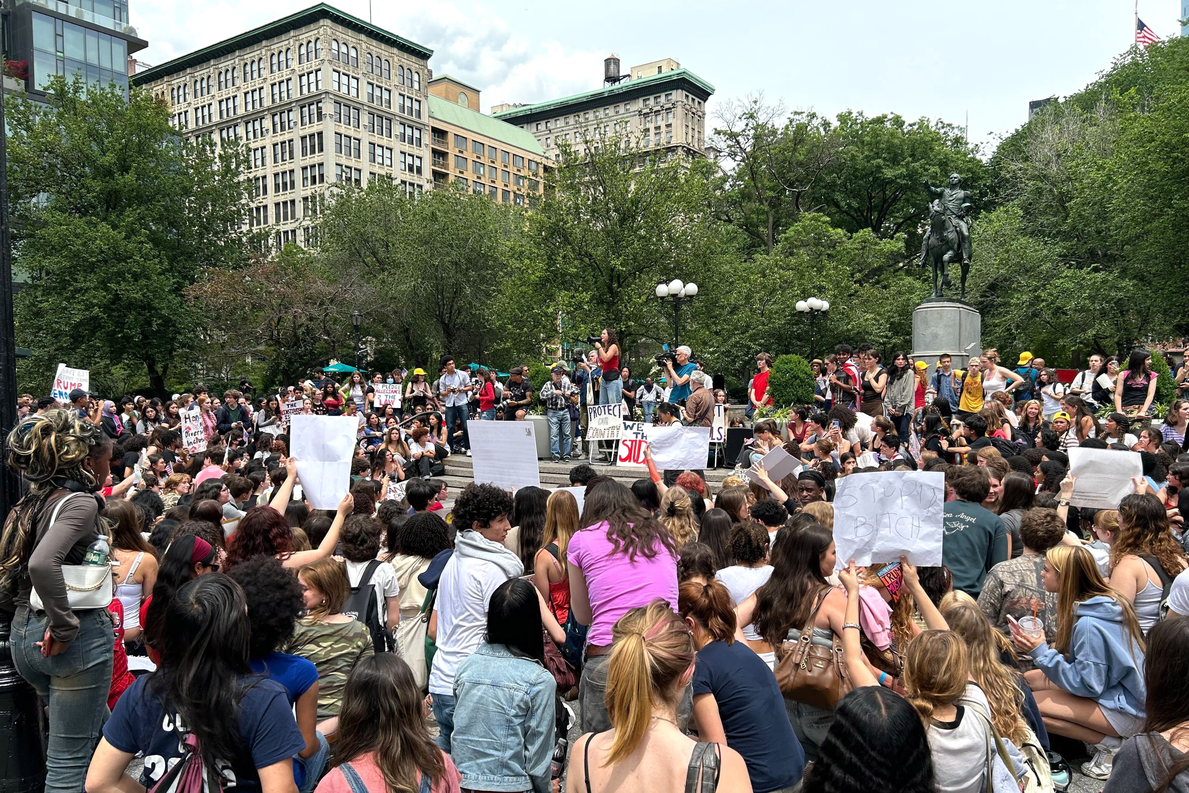 A huge crowd holds signs and listens to a speaker.