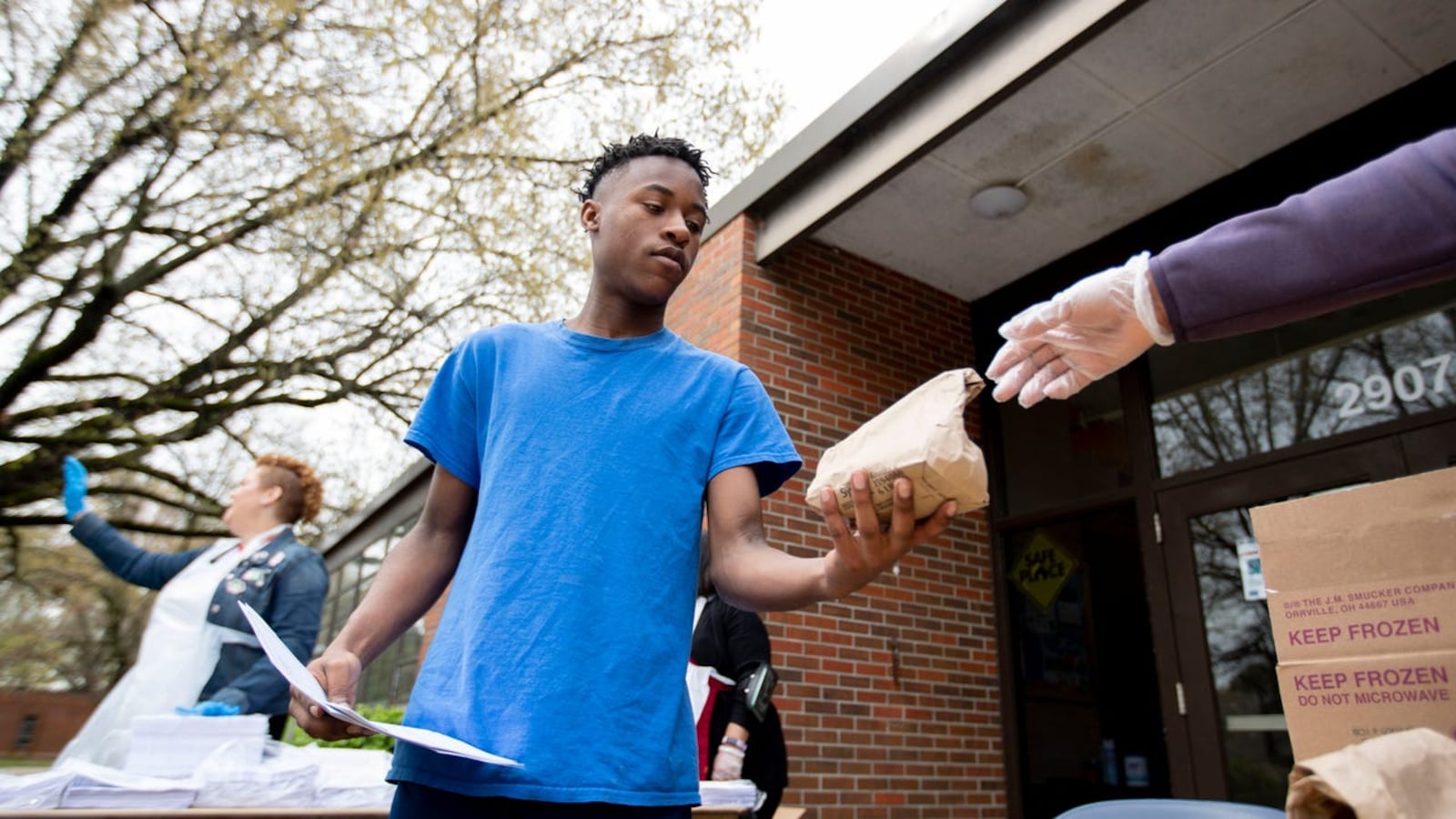 Ruby Buckner (right) of the YMCA of Memphis and the Mid-South hands a lunch to Demarius Hurd, 17, at Ed Rice Community Center in Memphis.
