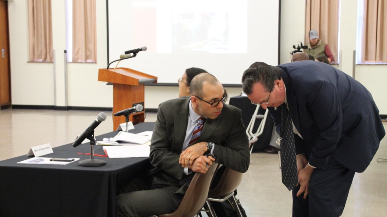 Brad Leon (left), the district's chief of strategy and performance management at a charter school hearing in 2019.