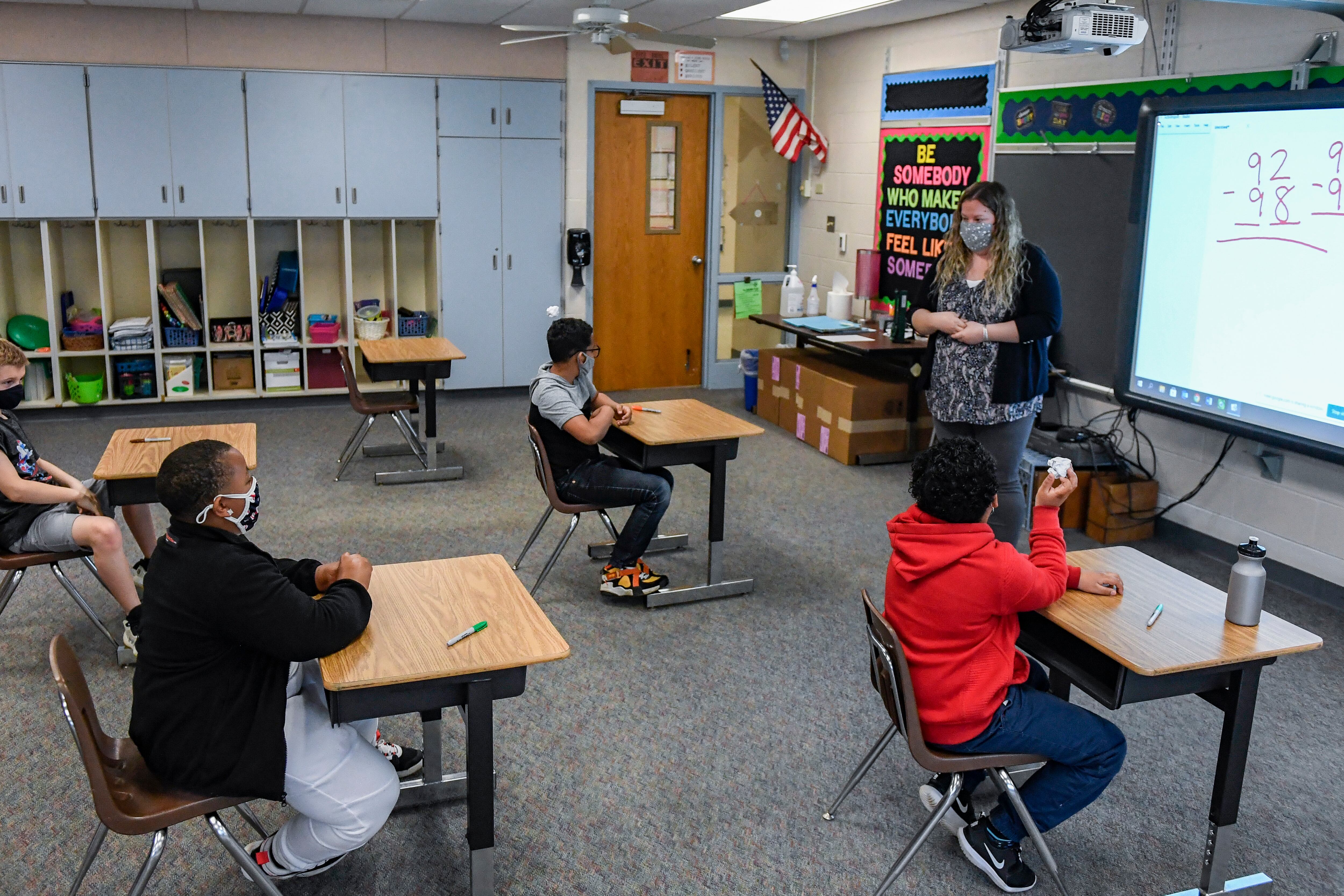 Students wear masks while sitting at desks in a class.