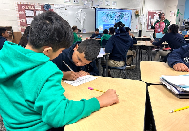 A group of students work at desks in a classroom.