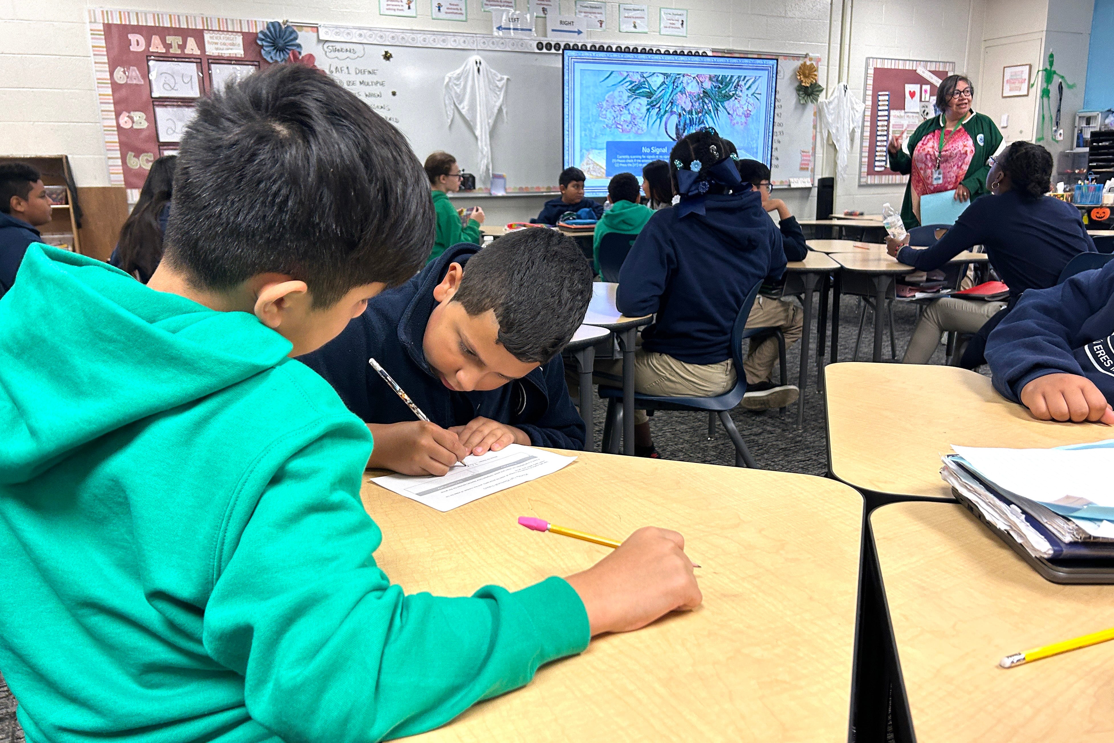 A group of students work at desks in a classroom.