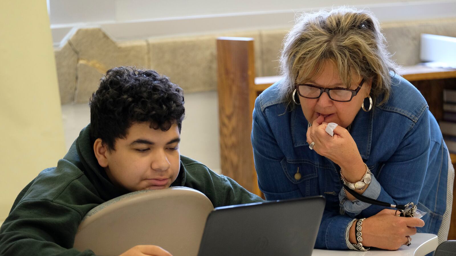 A teacher looks on as a student works at a laptop computer at Crispus Attucks High School, a public school in Indianapolis, Indiana. — April 2019 — Photo by Alan Petersime/Chalkbeat