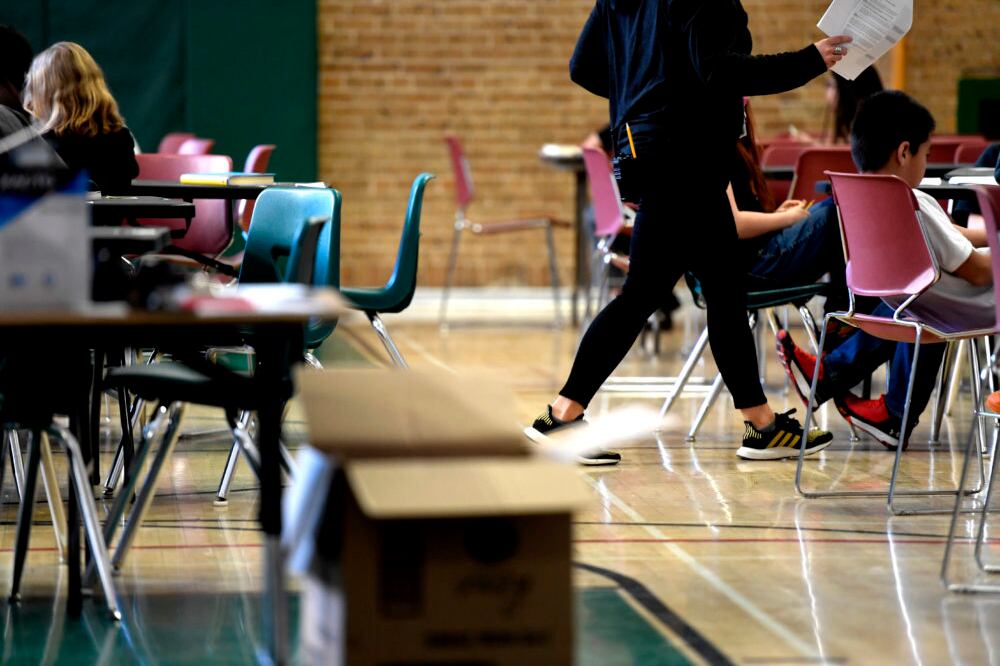 A teacher moves from table to table while teaching one of the two combined sixth grade classes in the gymnasium at Skinner Middle School during the first day of the Denver teacher strike.