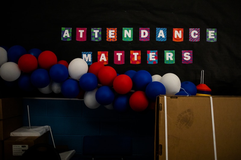 A garland of red, white, and blue balloons hangs in front of a sign that reads “Attendance matters.”