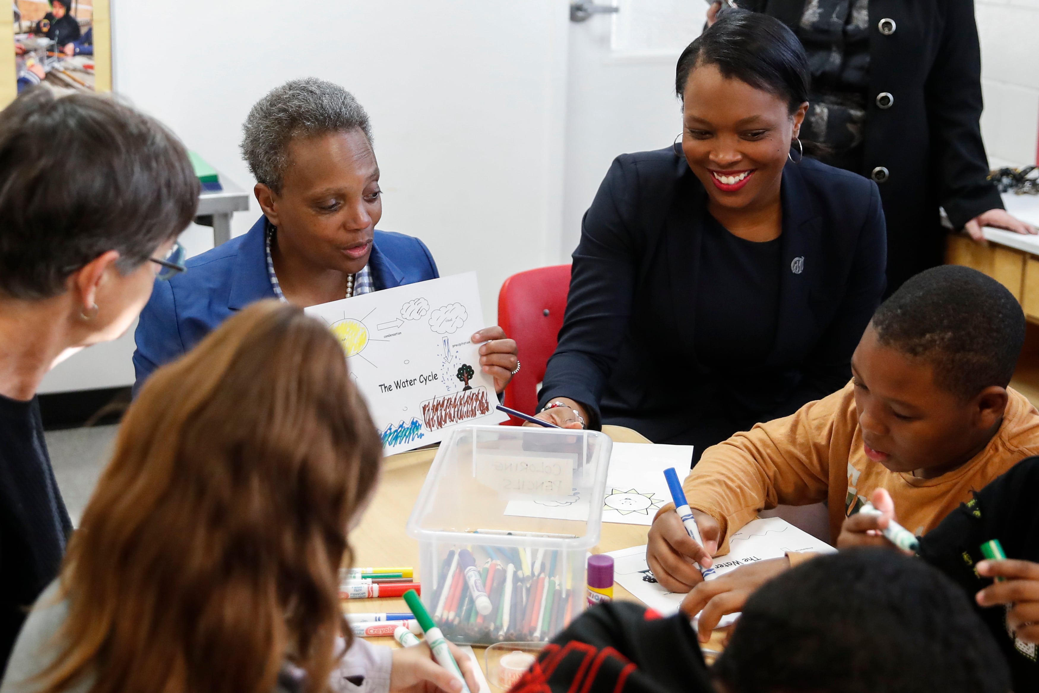 Janice Jackson sits next to Mayor Lori Lightfoot at a table with students.