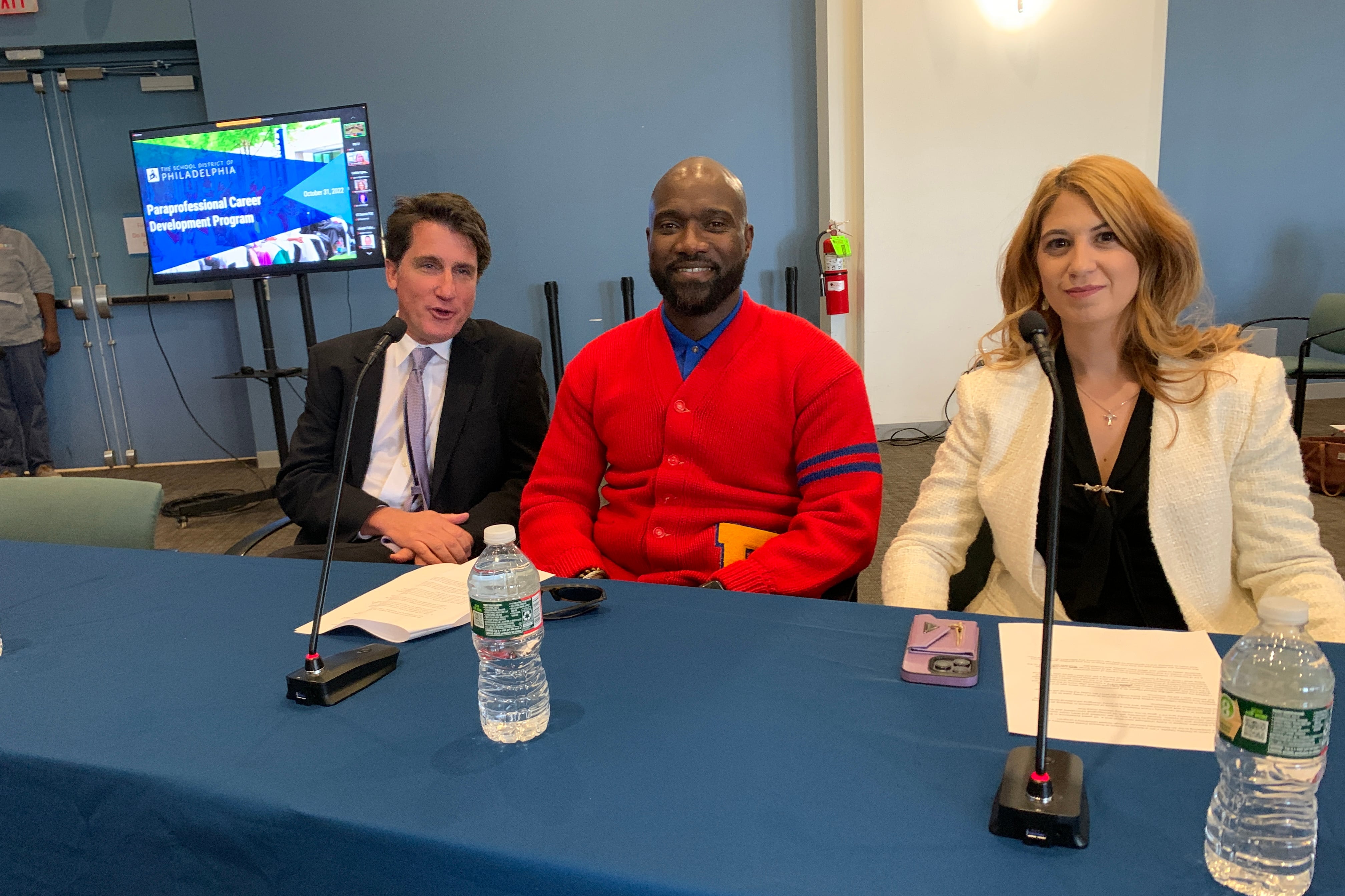 Three people sitting at a table waiting to testify at a hearing.