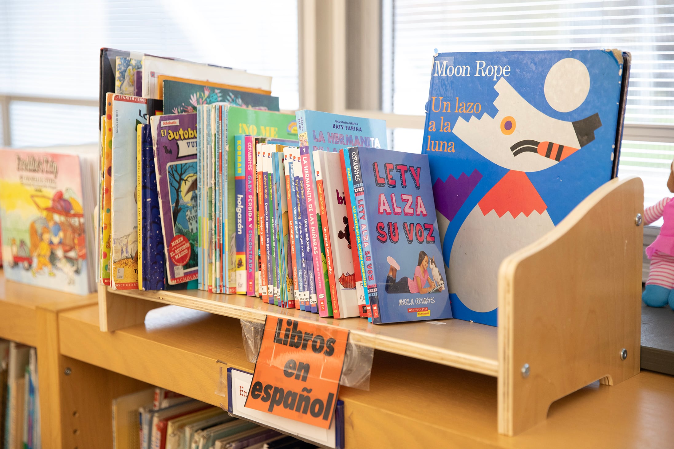 Children's books in Spanish on a shelf in an elementary school library.