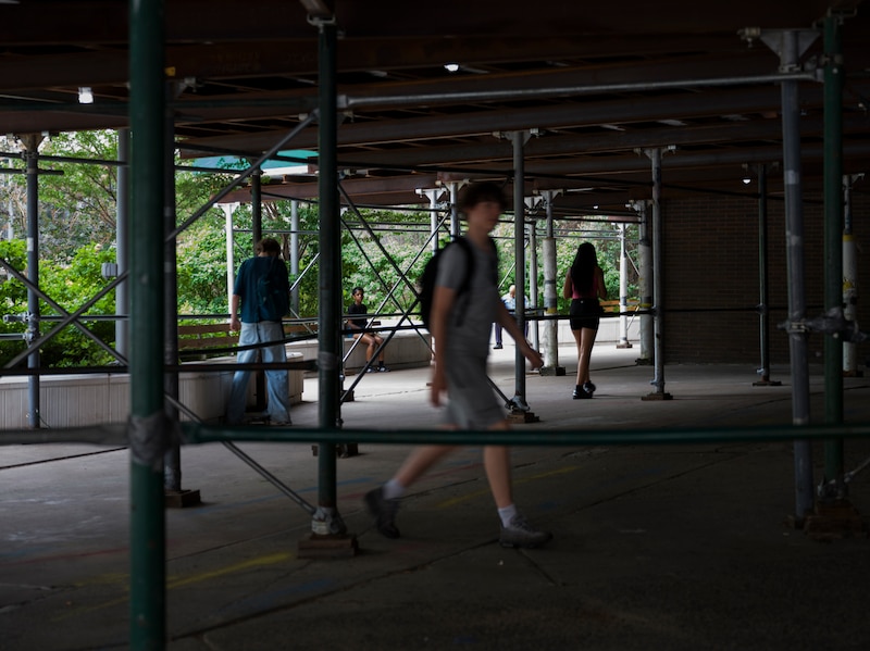 Students walking and leaving the school under the scaffolding.