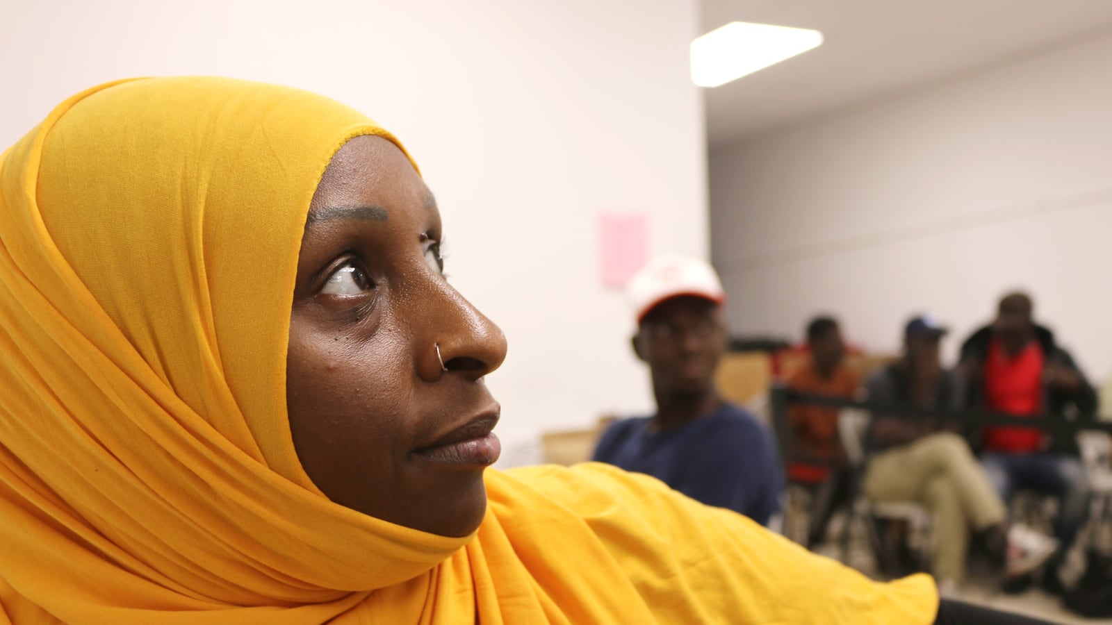 A woman in a gold-colored head covering looks to the side.