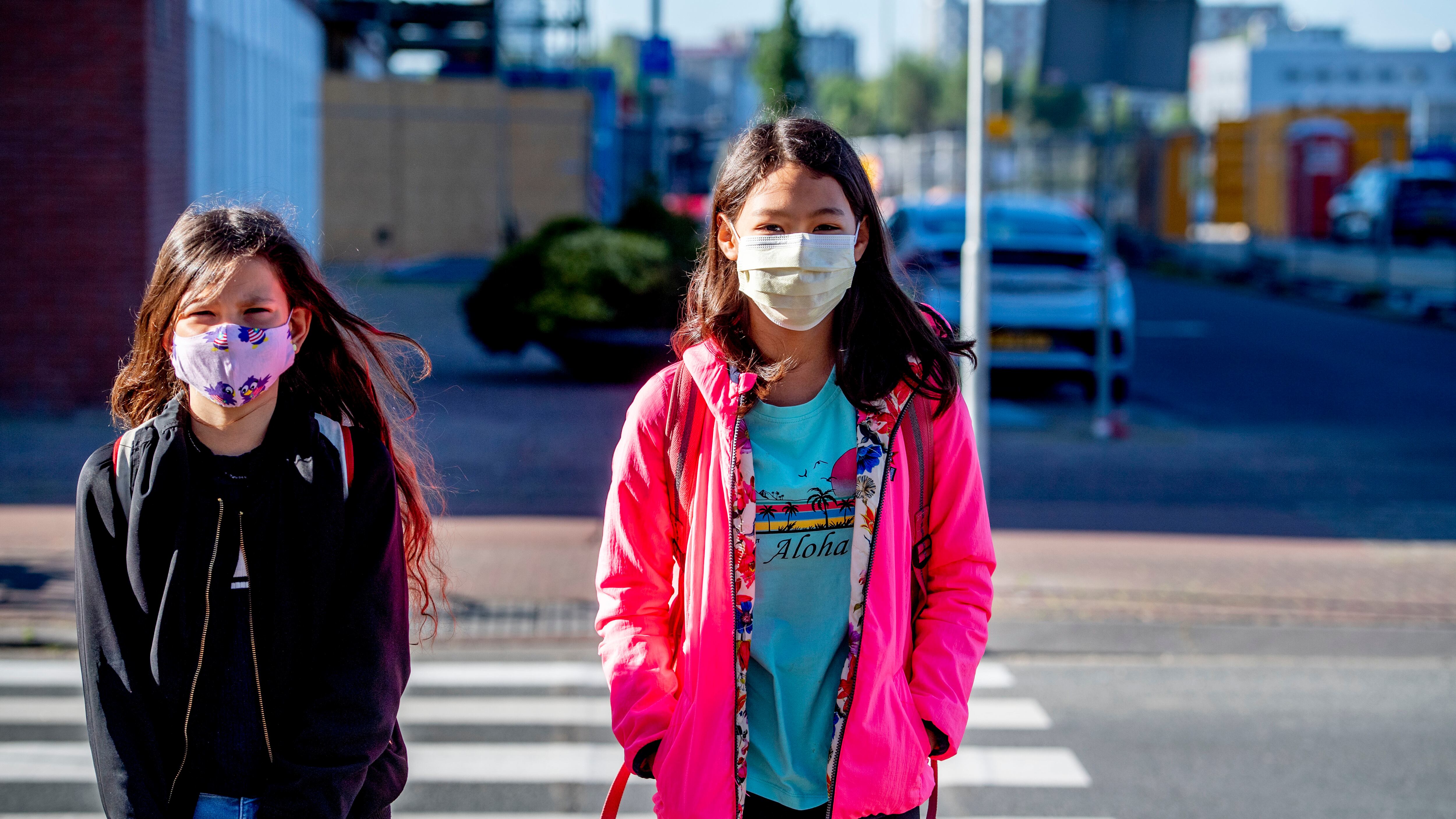 Children walk to school while wearing face masks as a...