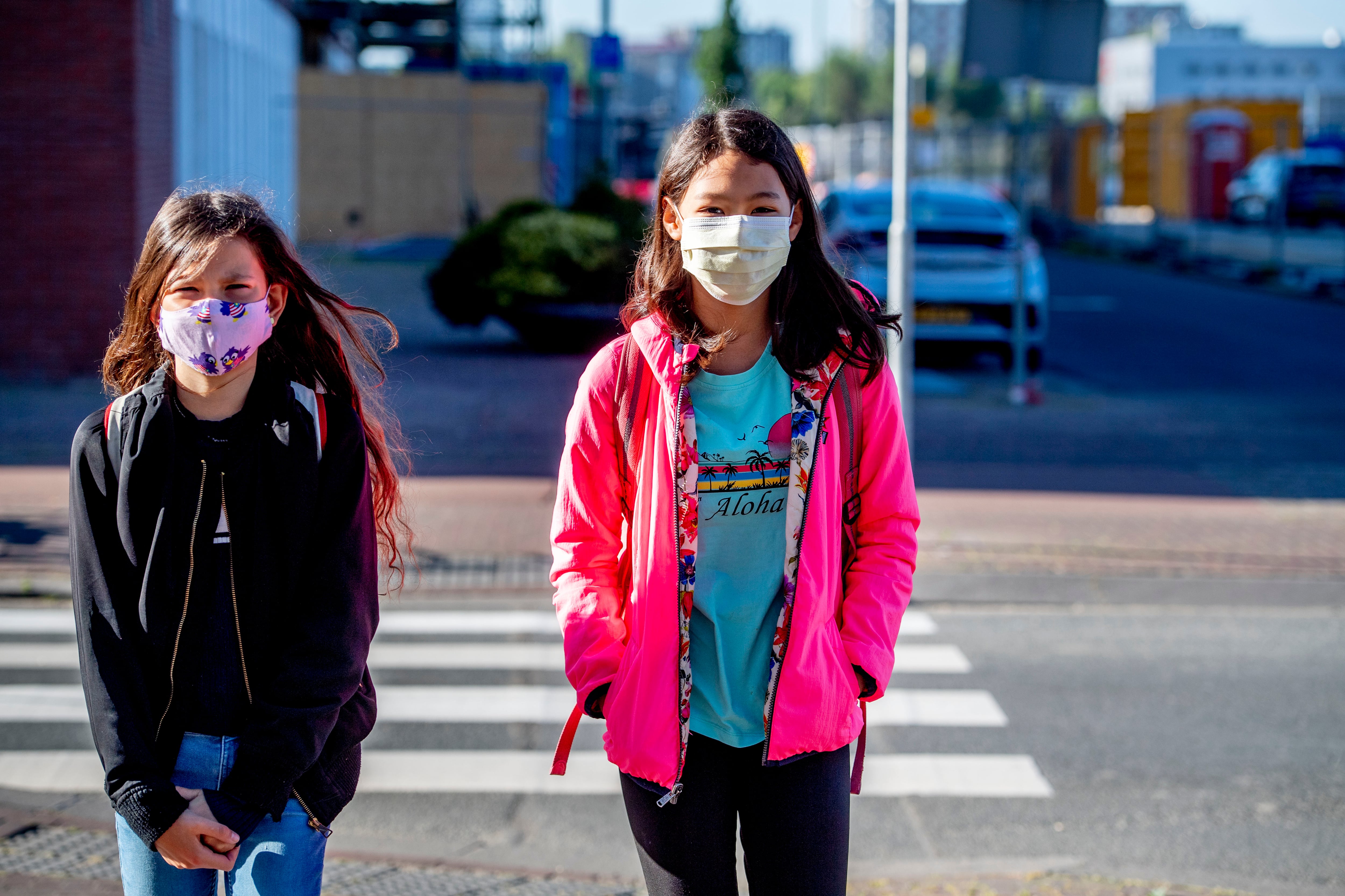 Children walk to school while wearing face masks as a...
