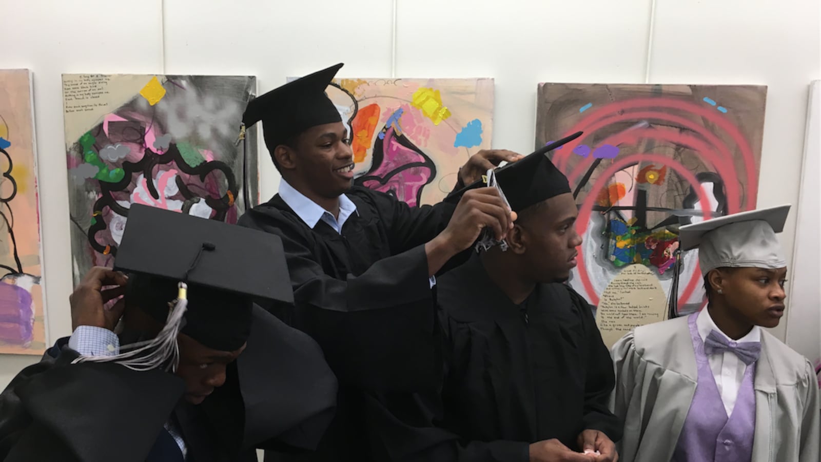 Jahrell Thomas, center, helps a classmate with his cap.