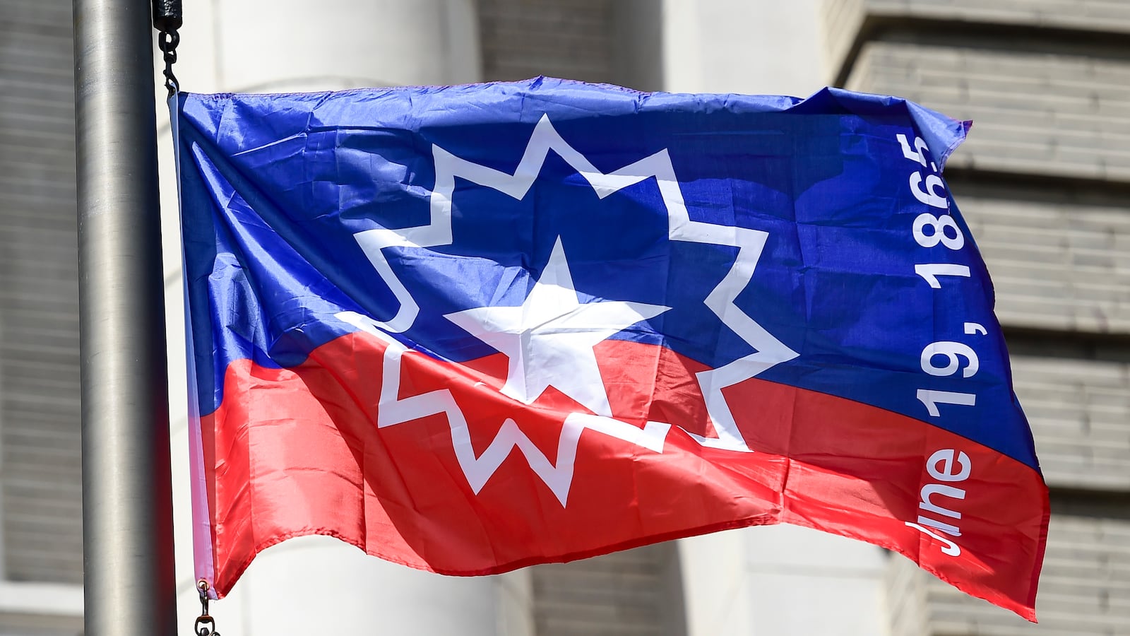 A blue and red Juneteenth flag features the date June 19, 1965.