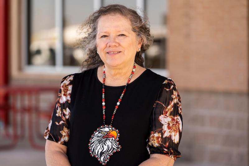 A woman poses for a portrait outside of a school building.